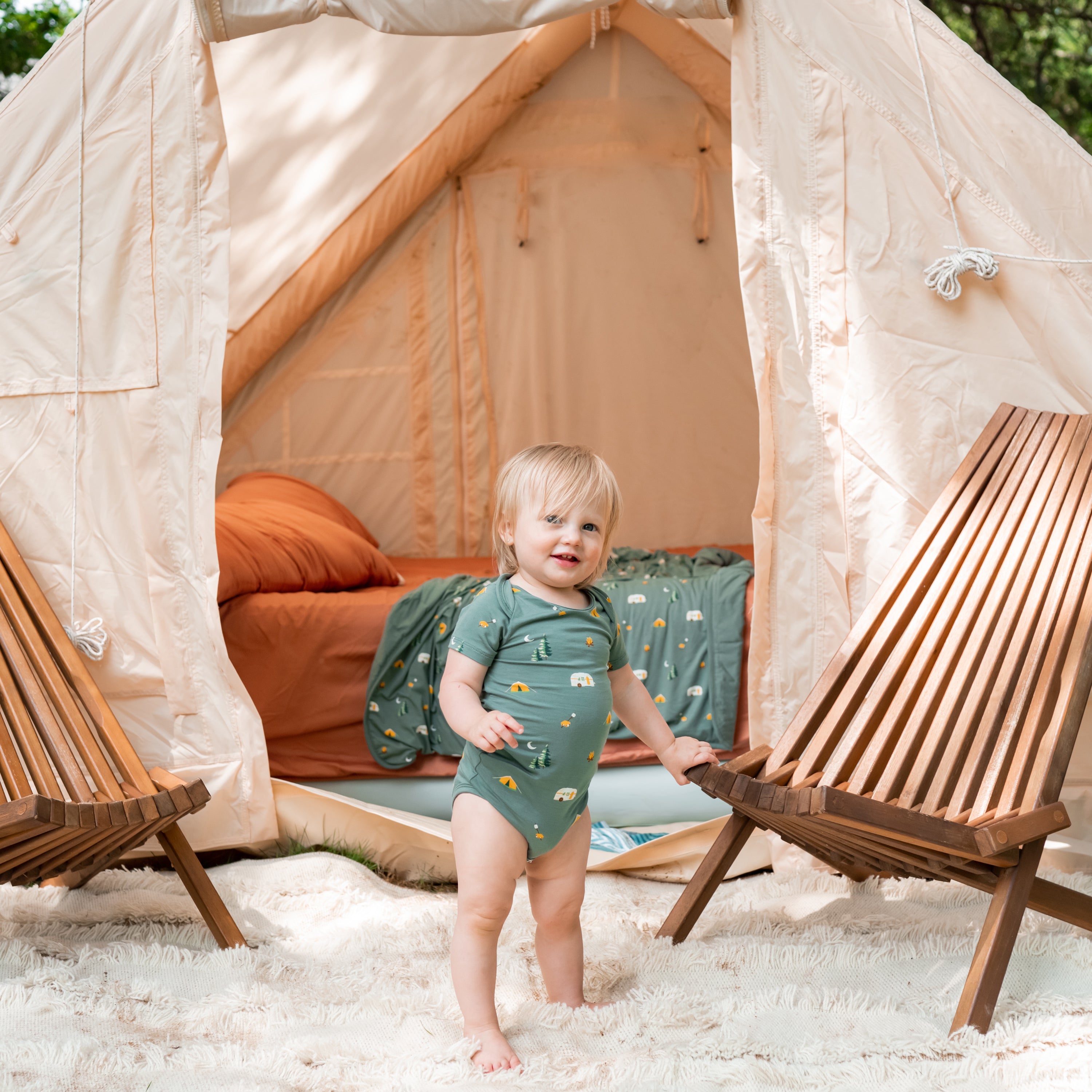 Child wearing Kyte Baby Camping Bodysuit outside campsite