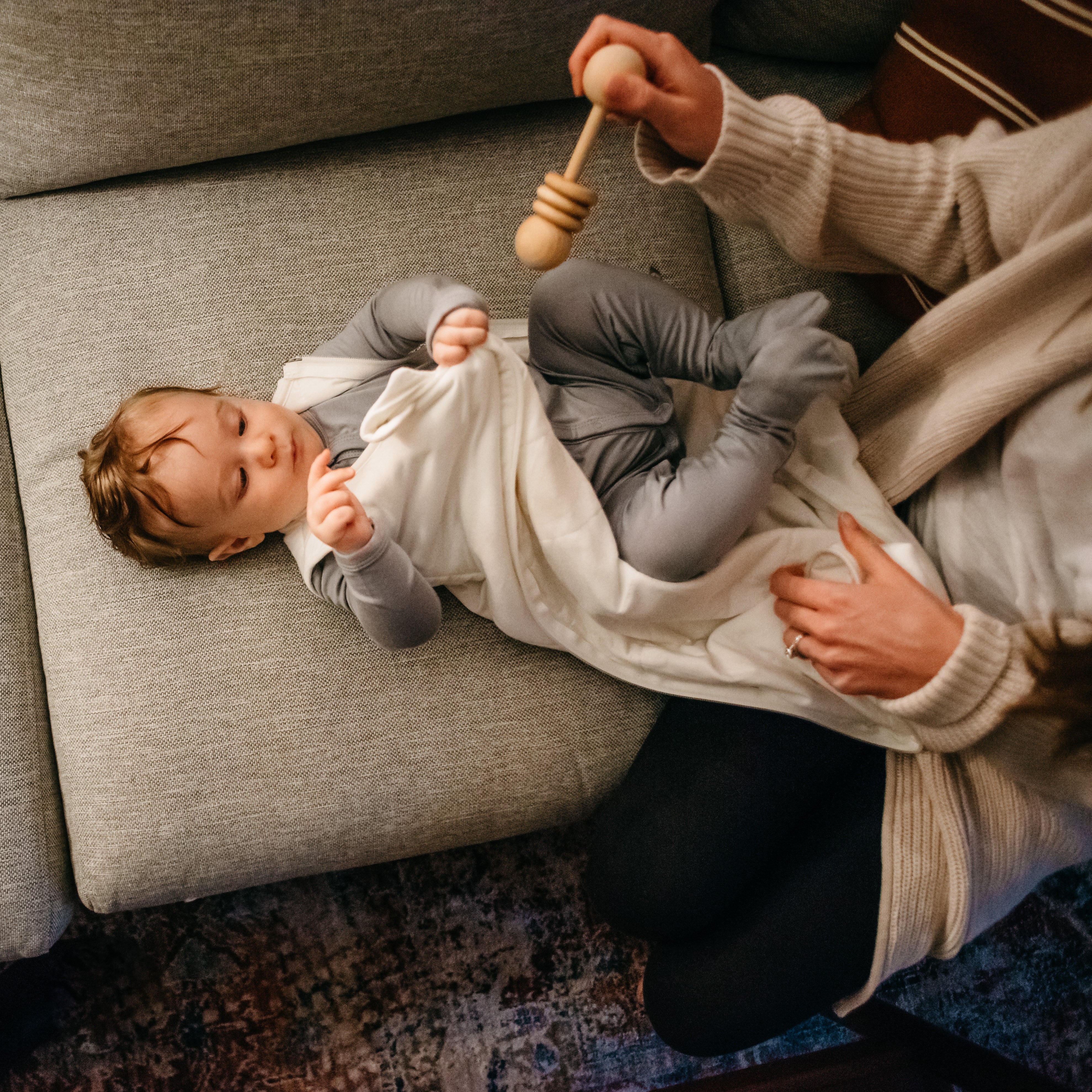 mom holding a wooden rattle above babys face