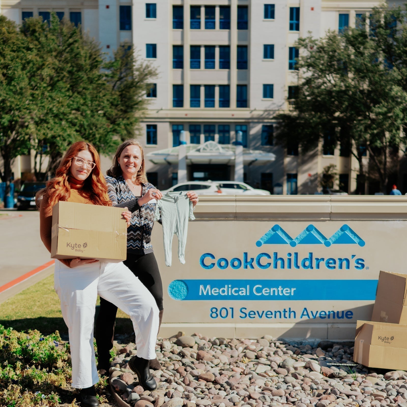 Willow, kyte baby's marketing manager, standing in front of cook children's medical center with a box of clothing donations
