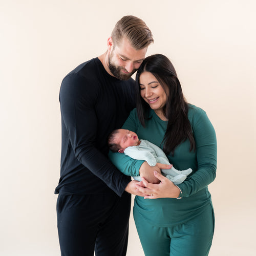 dad standing next to his wife and holding their baby