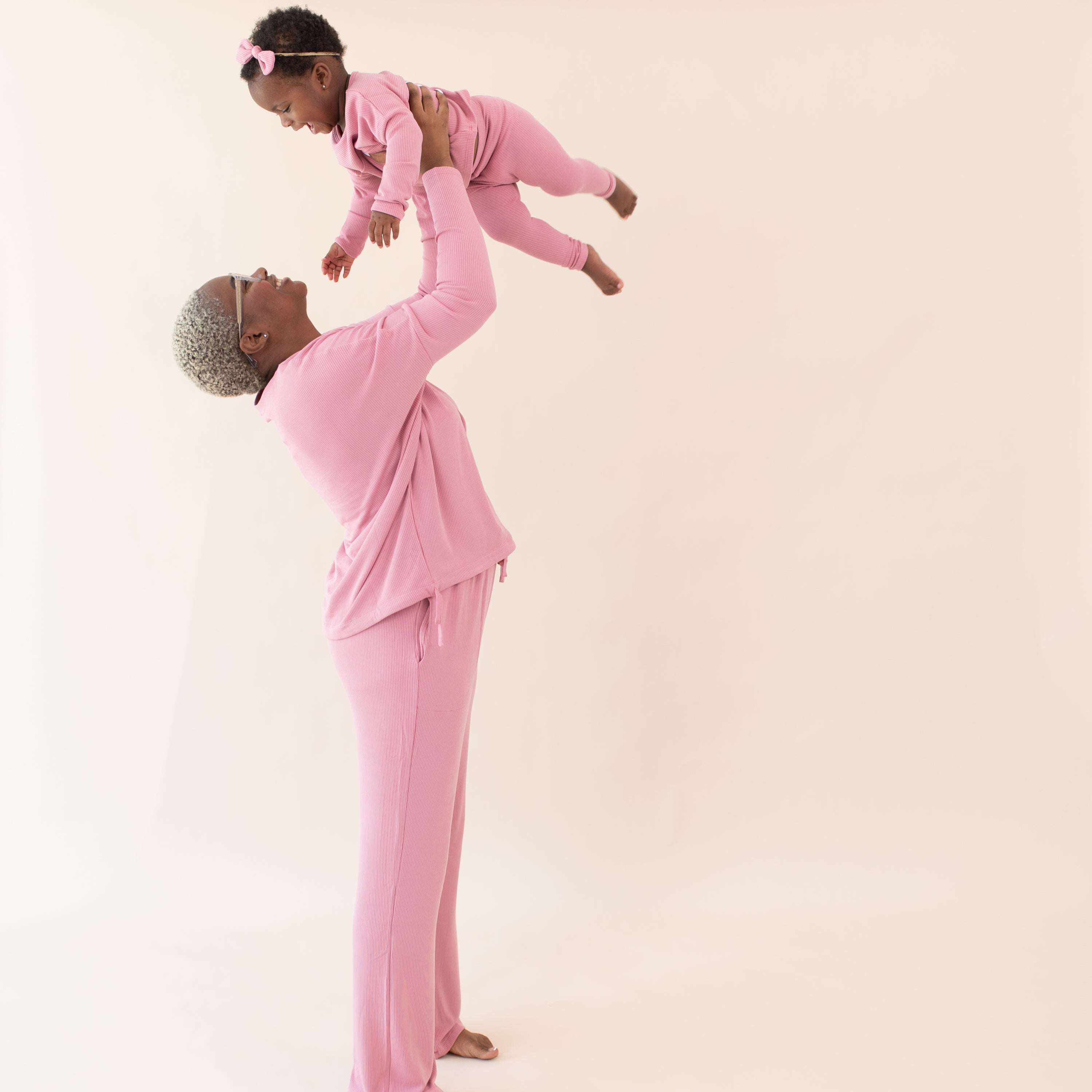 Mom holding up baby wearing matching Kyte Baby apple blossom ribbed outfits