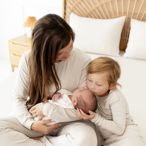 Mom with toddler and newborn baby all wearing coordinating Kyte Baby clothing