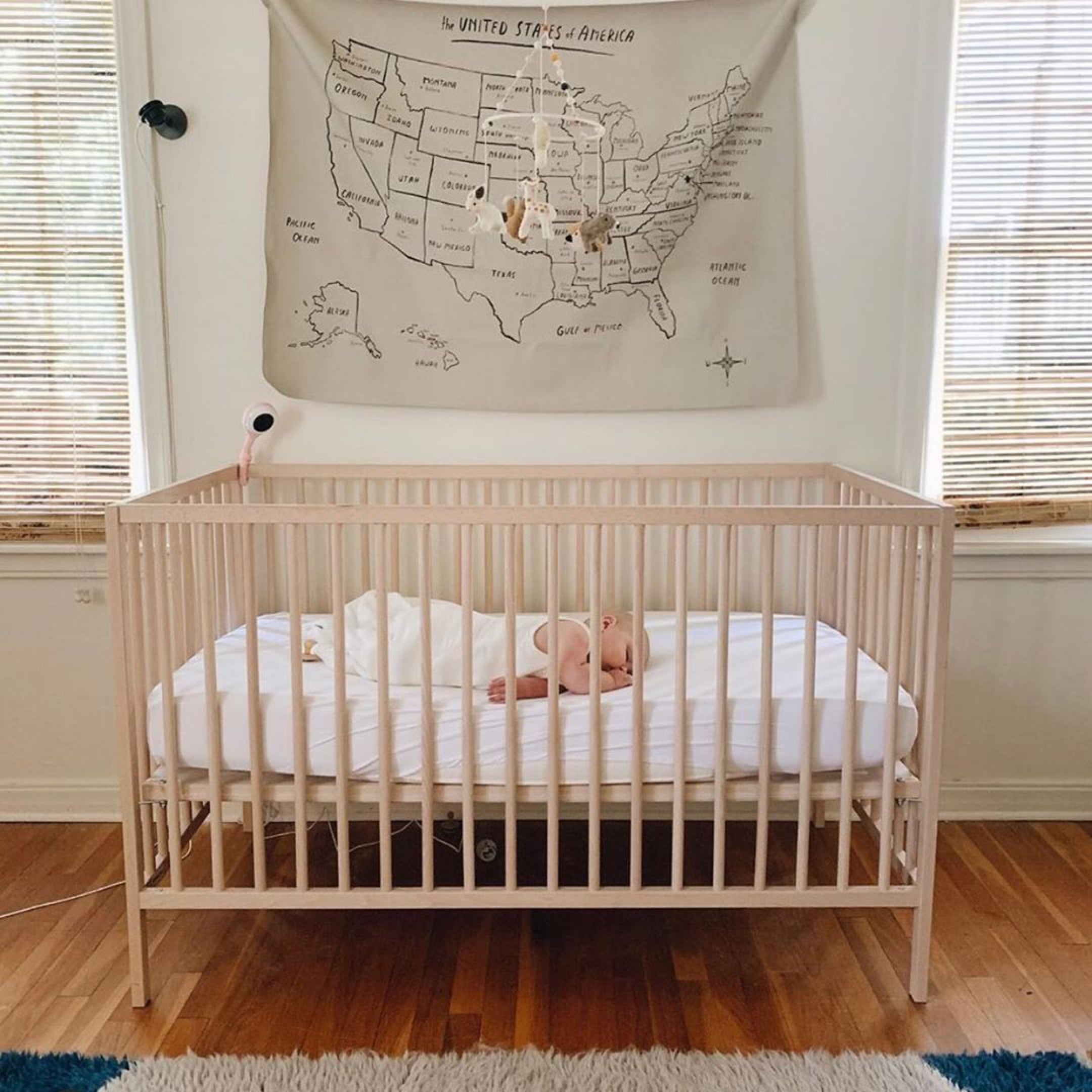 Baby sleeping in crib wearing a white sleep bag