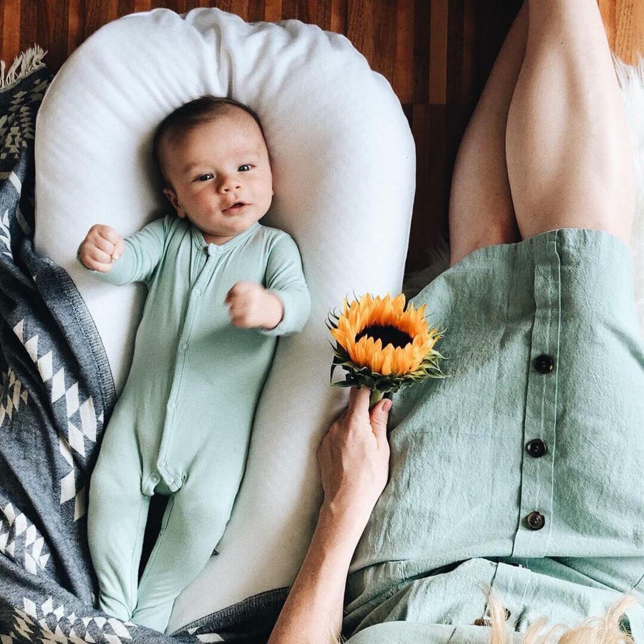 mother sitting next to baby laying in a dock a tot