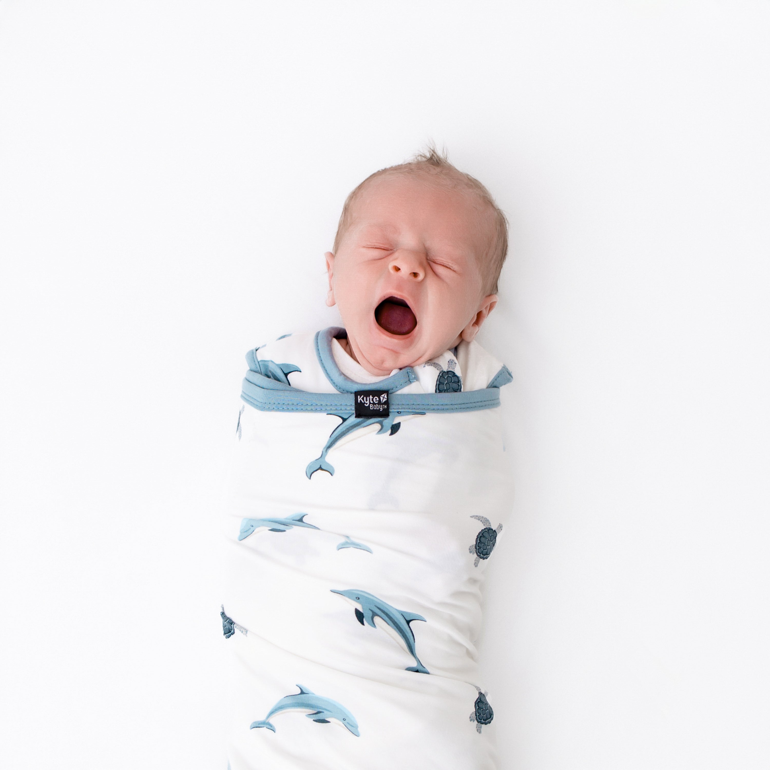 close up of 0.5 sleep bag swaddler in dolphin on a yawning baby