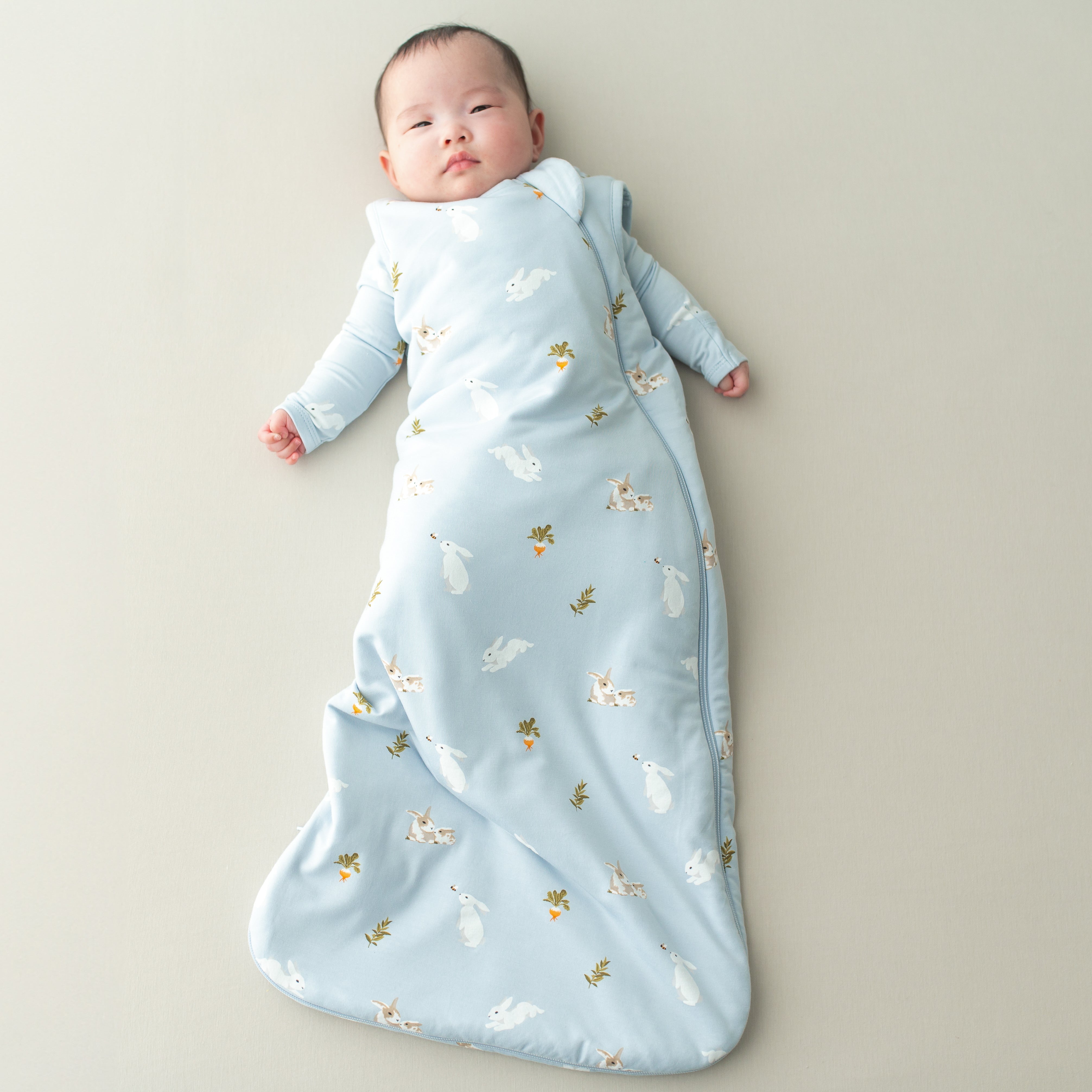 Baby wearing the Sleep Bag in Ice Rabbit 1.0 with Ice Rabbit long sleeve romper underneath