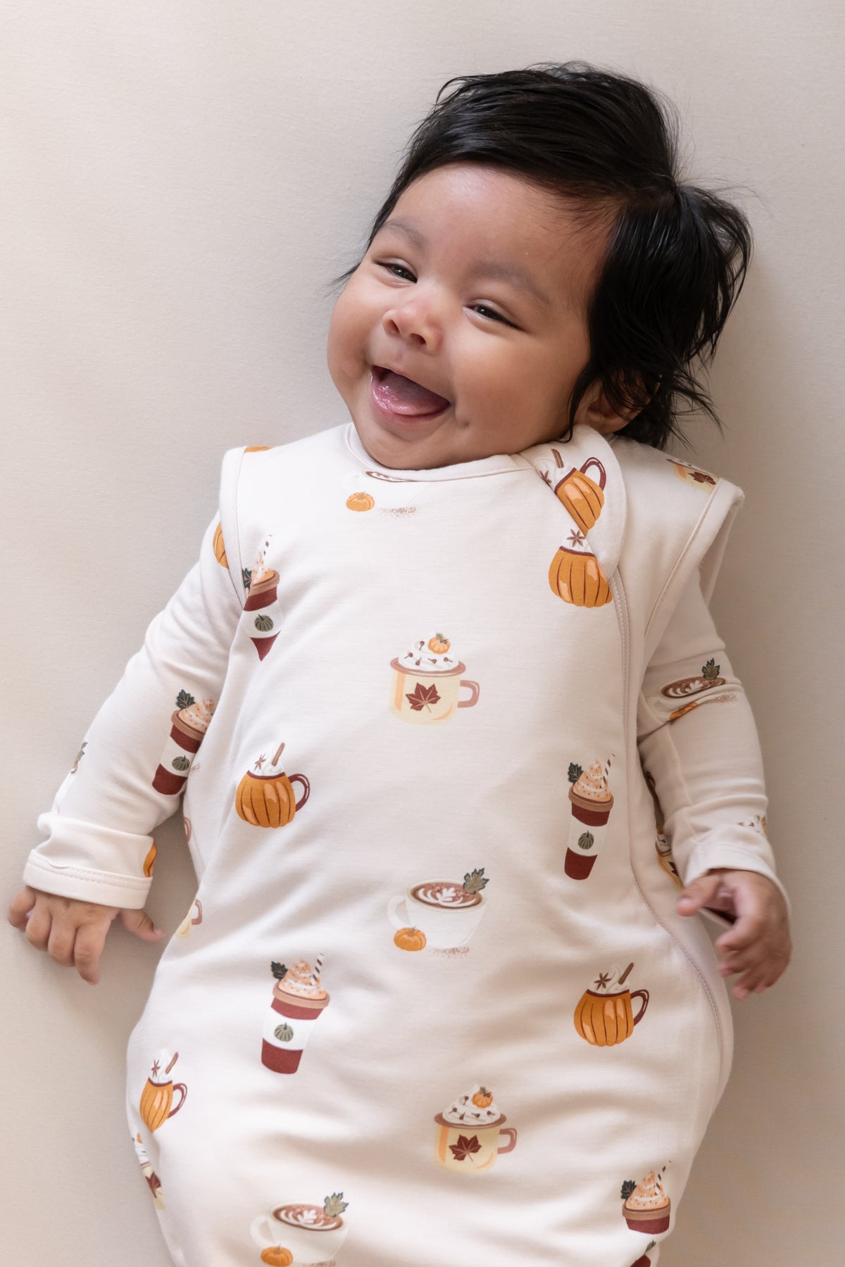 Close up of Baby wearing Sleep Bag with Pumpkin Spice Latte 1.0 print on a beige sheet