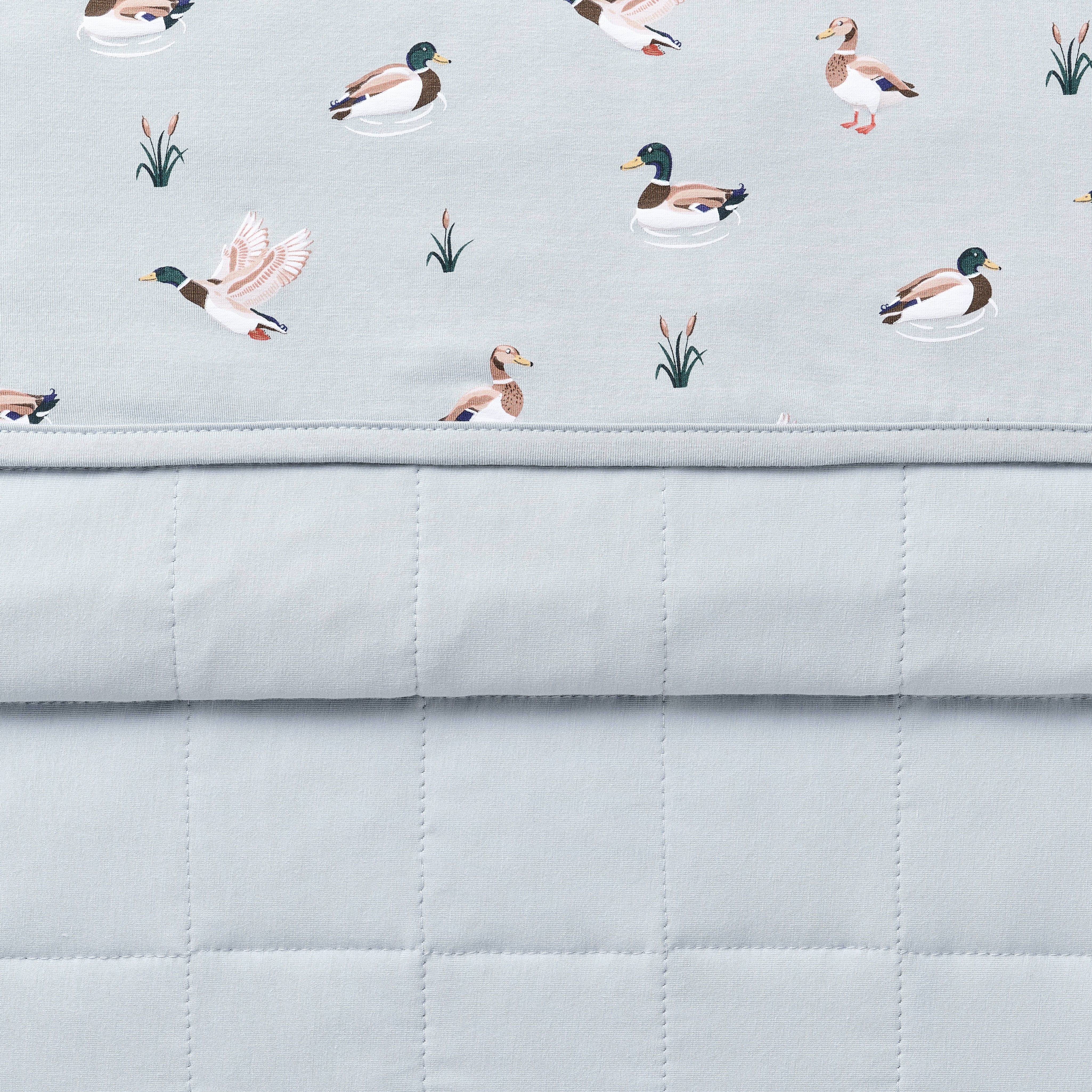 Close up of the Baby Blanket in Mallard Duck showing the quilted blue backing and patterned smooth top layer