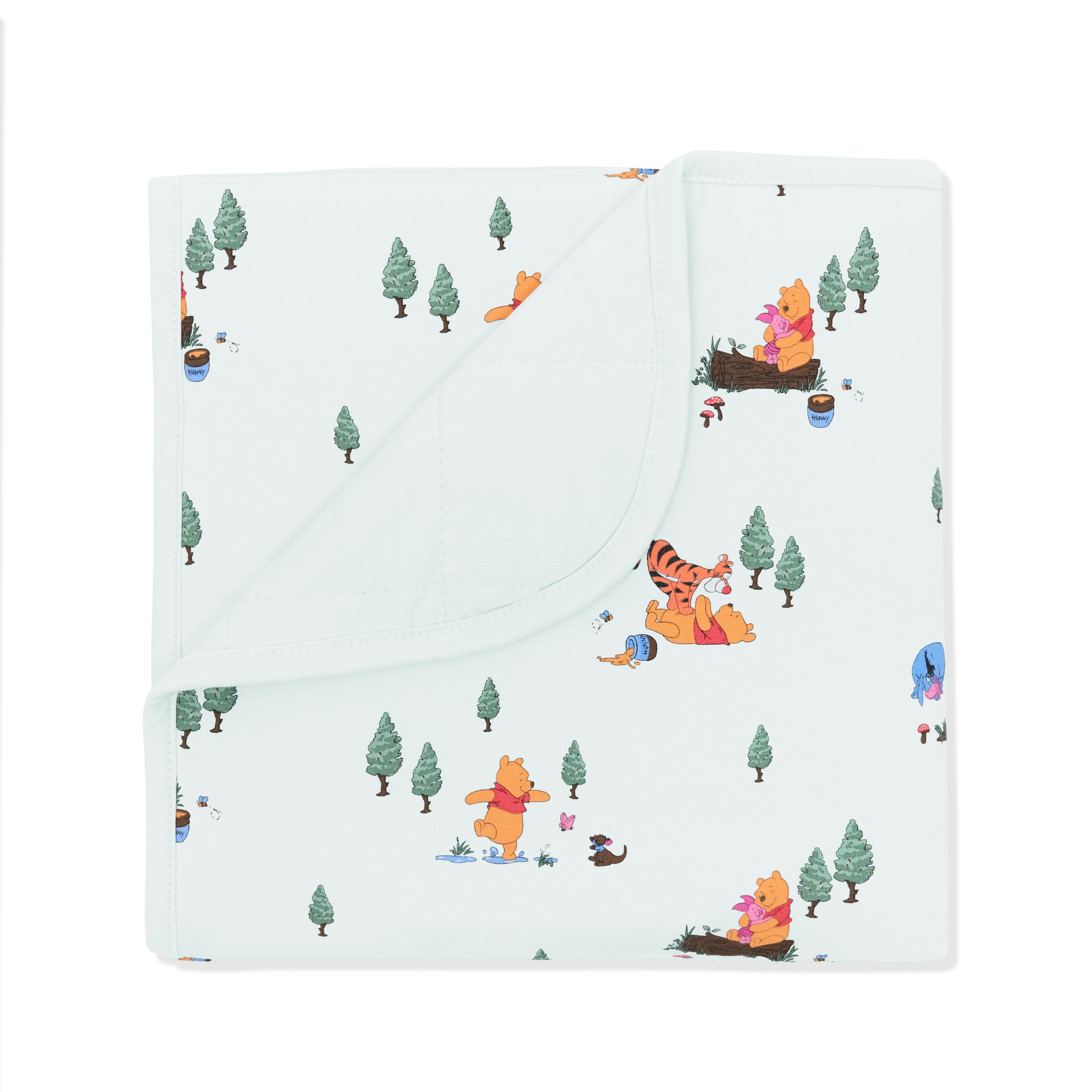 Baby Blanket in Winnie the Pooh Hundred Acre Wood with the corner folded down showing the light green backing