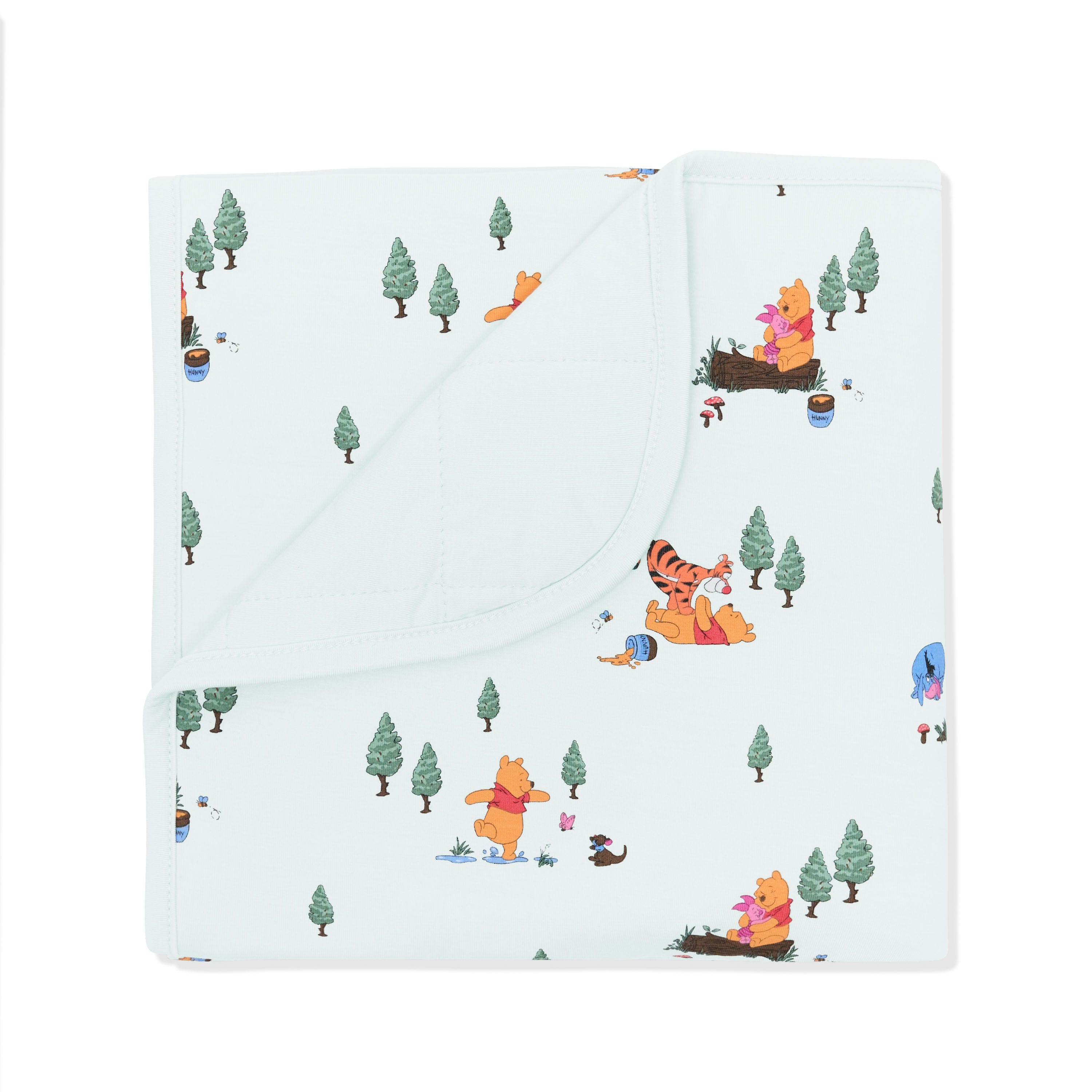 Baby Blanket in Winnie the Pooh Hundred Acre Wood with the corner folded down showing the light green backing