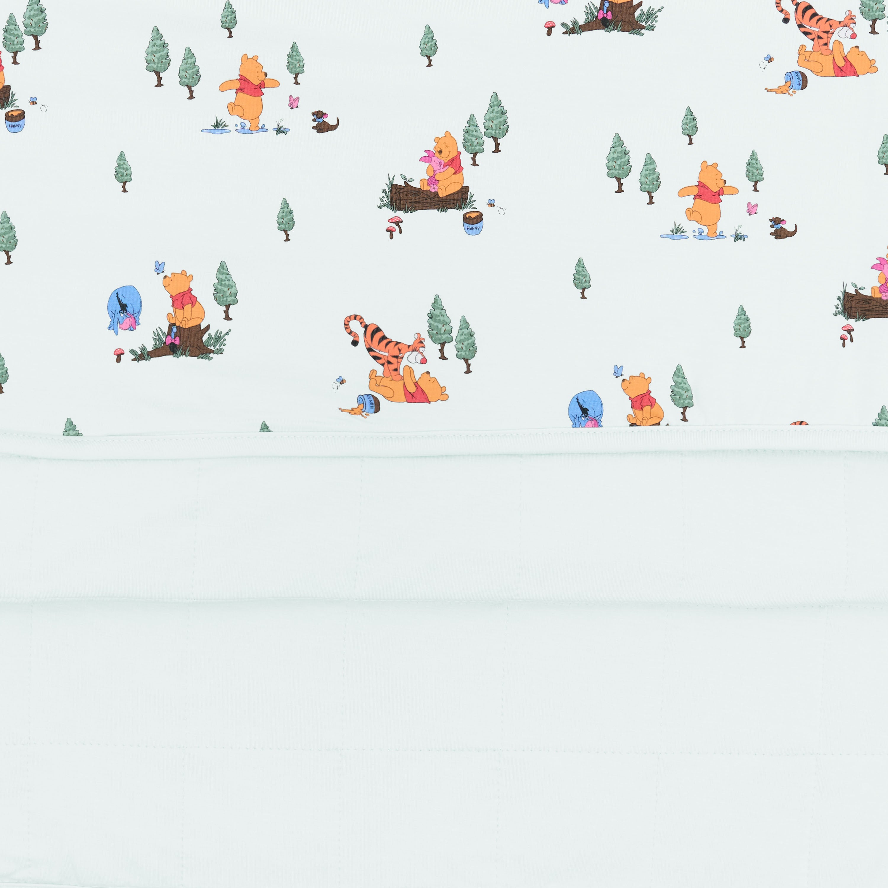 Close up of the Baby Blanket in Winnie the Pooh Hundred Acre Wood showing the light green quilted backing and printed smooth top layer