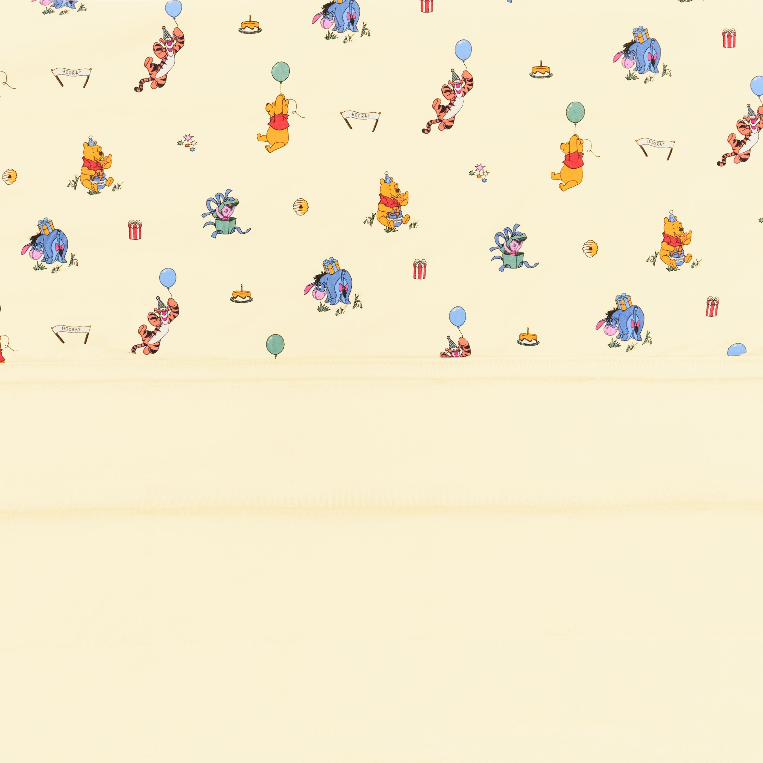 Close up of the Baby Blanket in Winnie the Pooh Celebration showing the light yellow quilted backing and smooth printed top layer