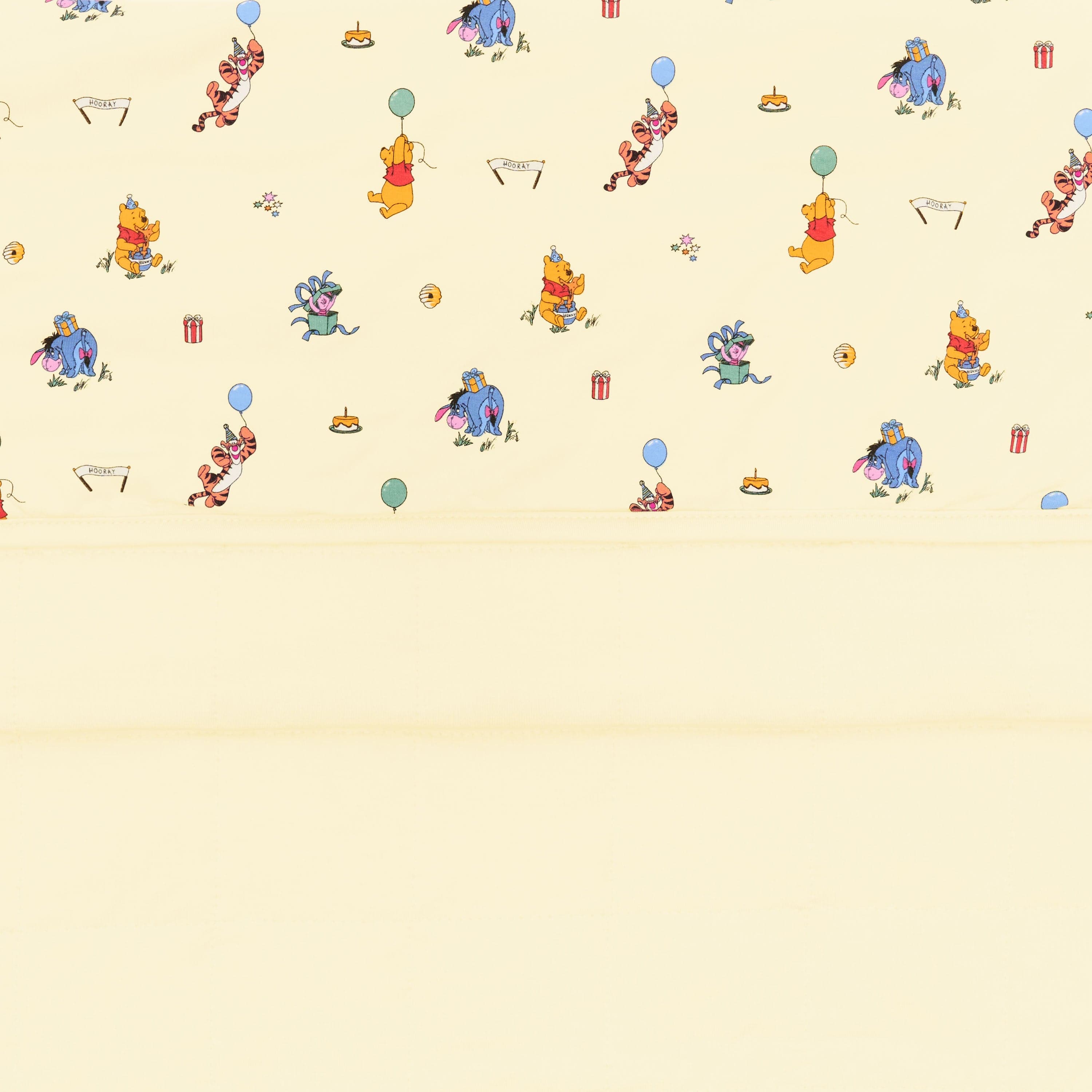 Close up of the Baby Blanket in Winnie the Pooh Celebration showing the light yellow quilted backing and smooth printed top layer