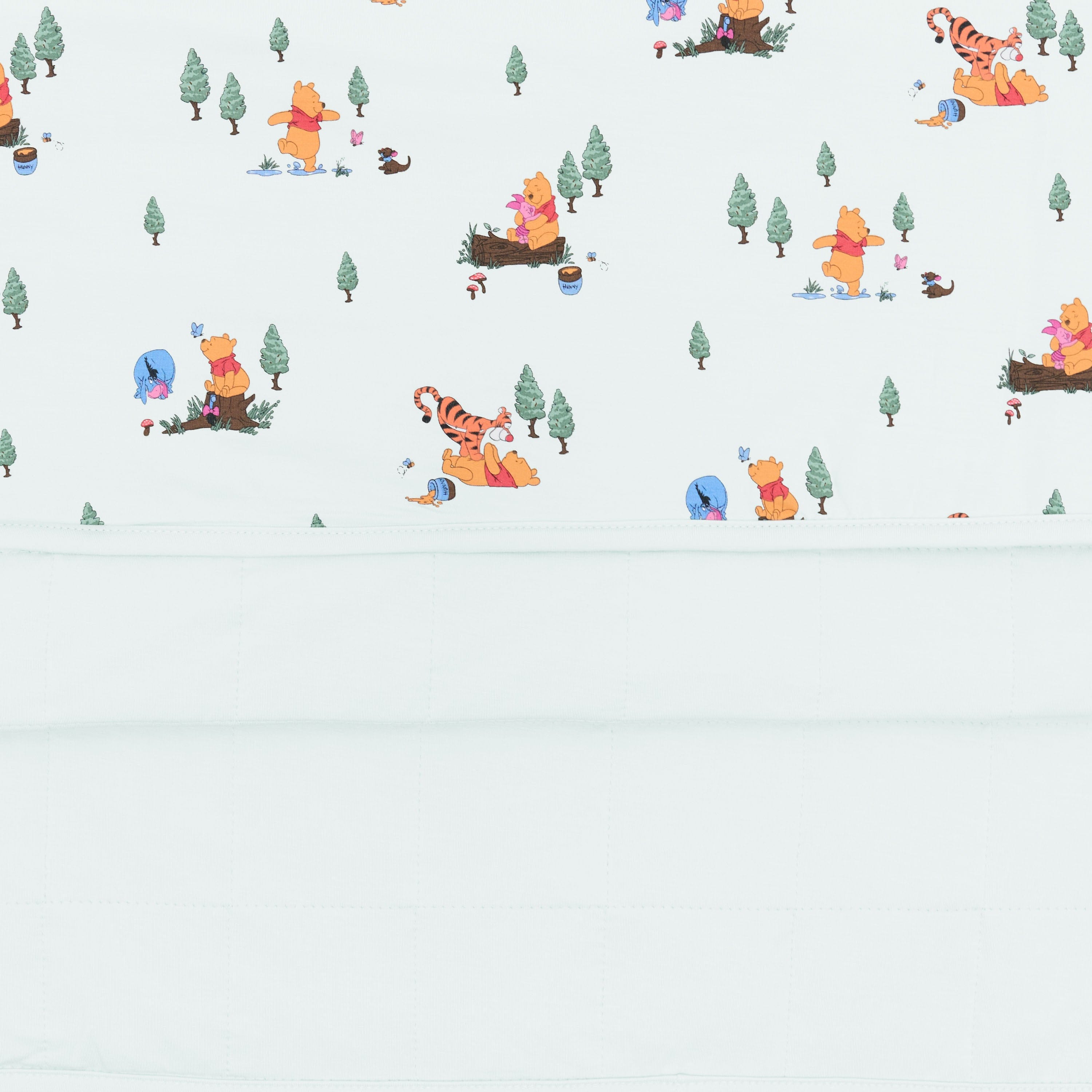 Close up of the Toddler Blanket in Winnie the Pooh Hundred Acre Wood 1.0 showing the light green quilted backing and printed top smooth layer