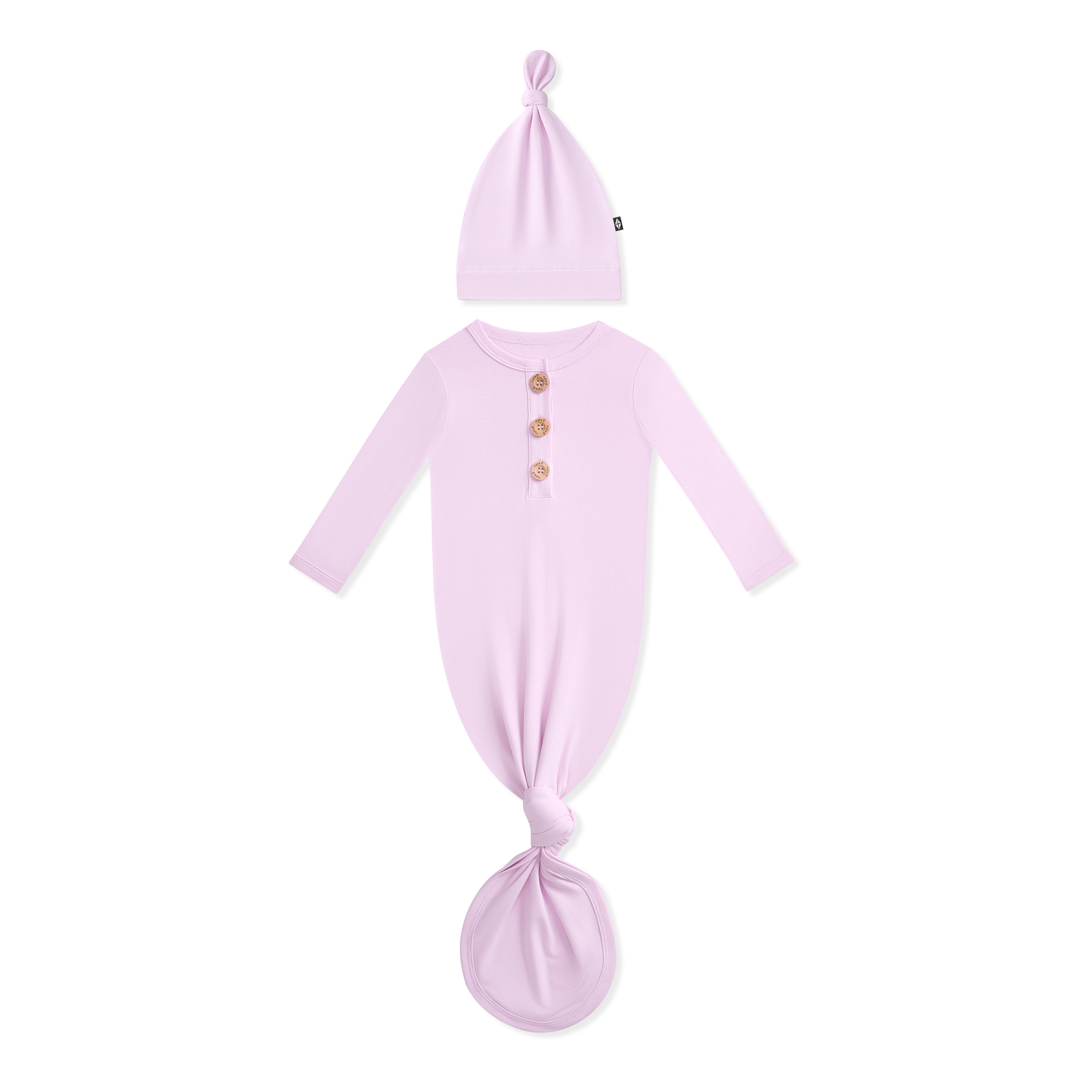 Baby outfit with purple knotted dress and matching hat on a white background