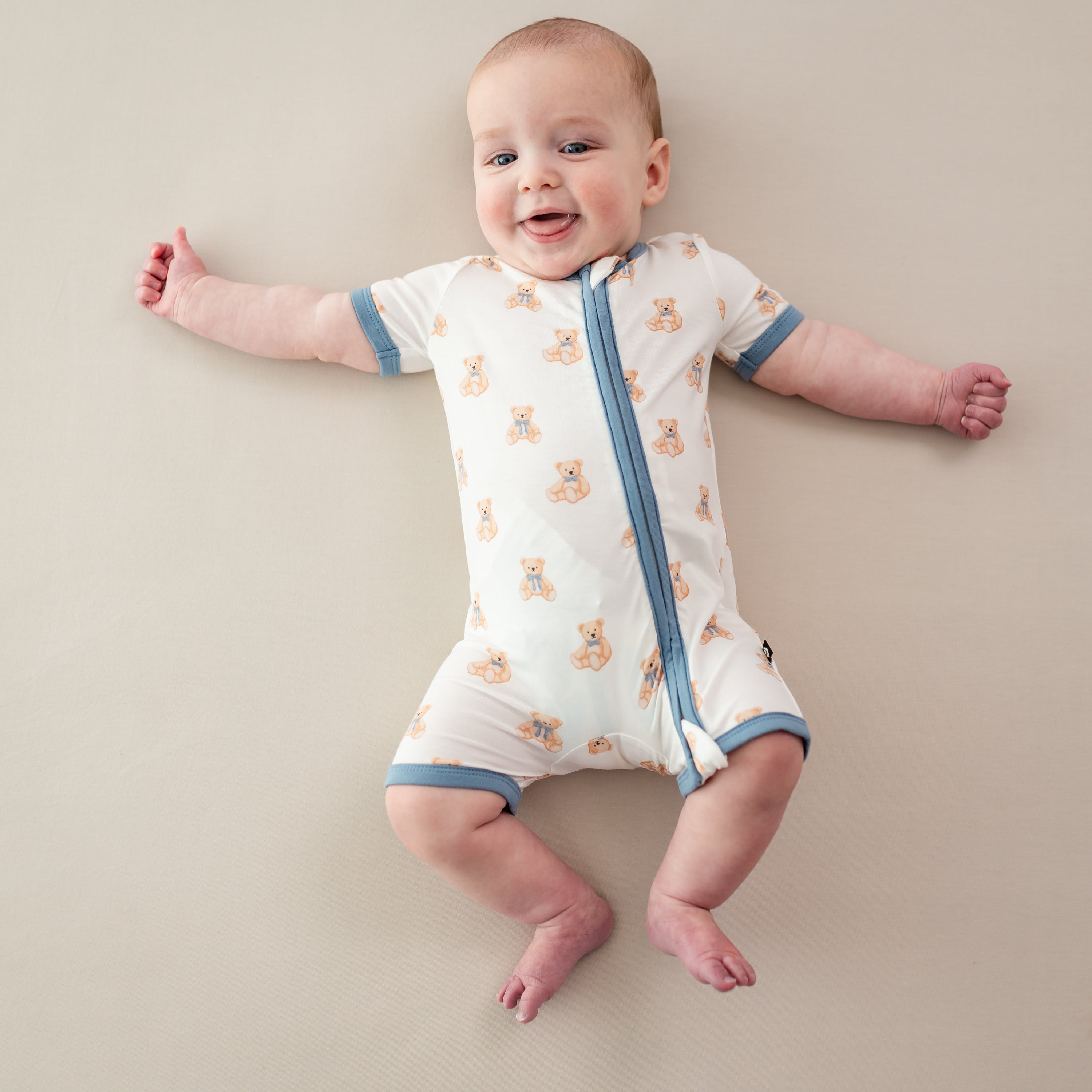 Infant wearing Kyte Baby Zippered Shortall Romper in Teddy Bear