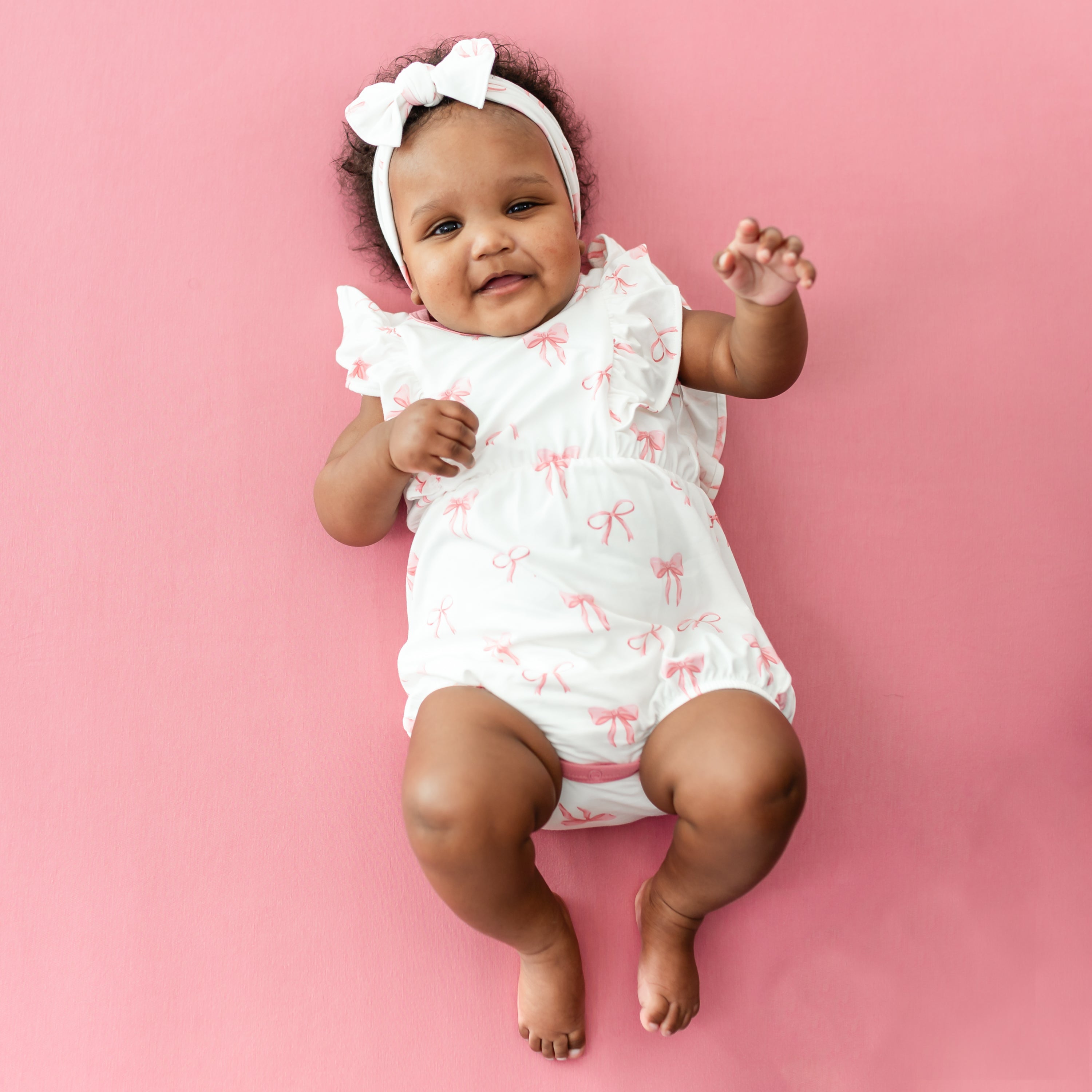 Baby wearing Bubble Romper in Bow print with matching knotted bow headband
