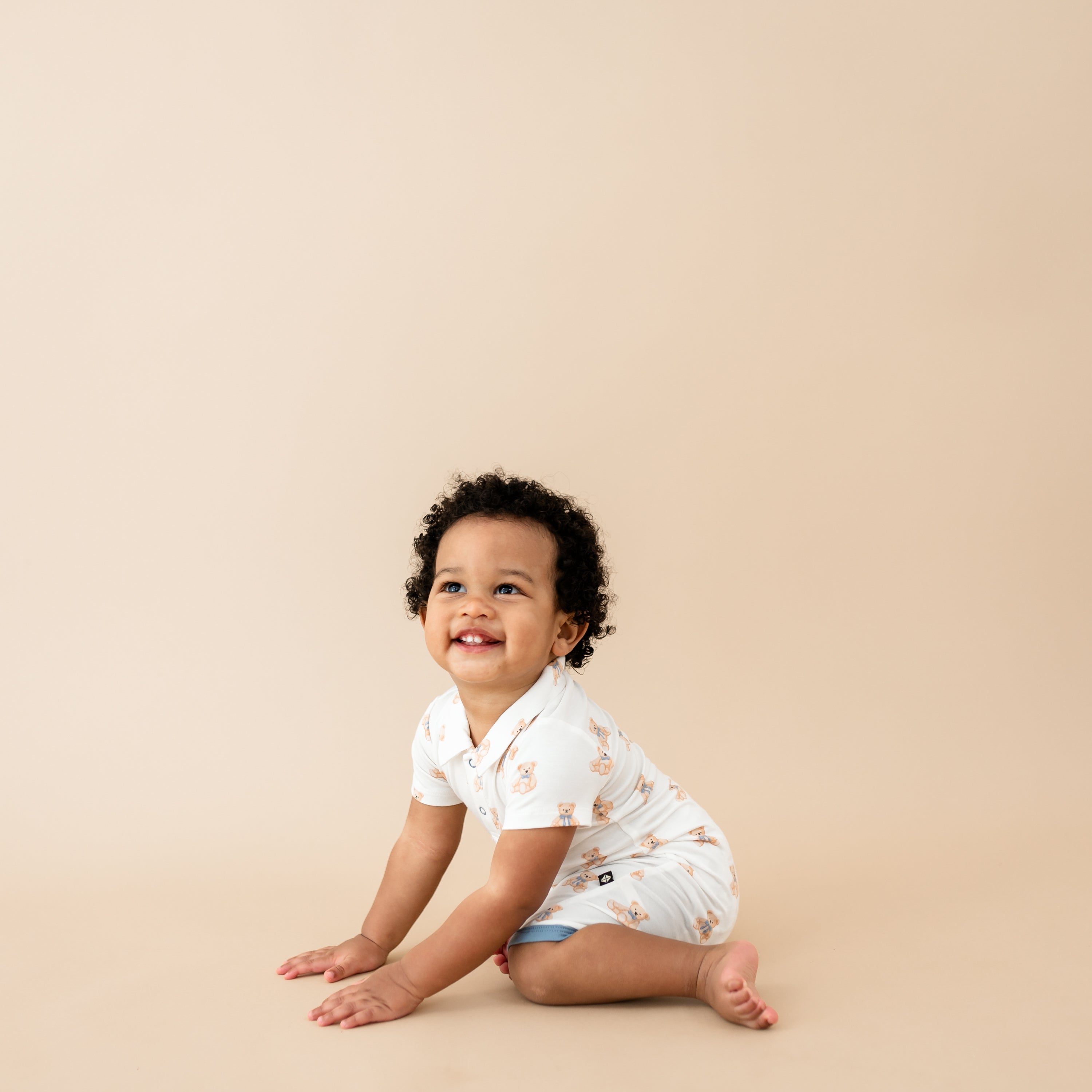 Toddler sitting smiling wearing Polo Shortall in Teddy Bear