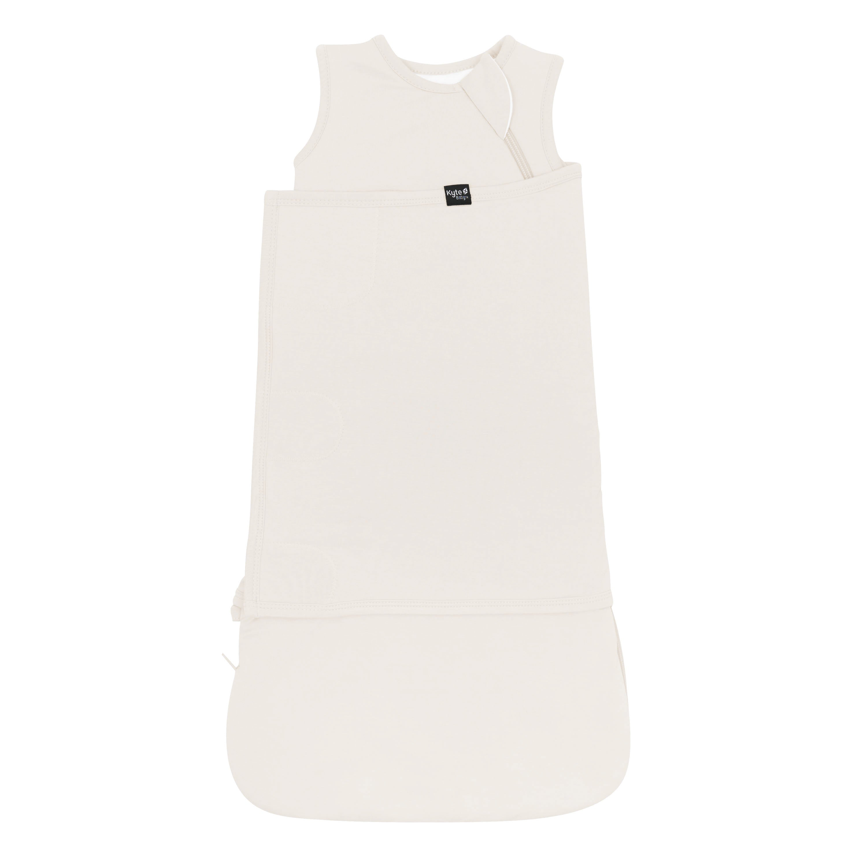 Sleep Bag Swaddler in Oat 1.0 shown swaddled with the Black Kyte Baby tag visible