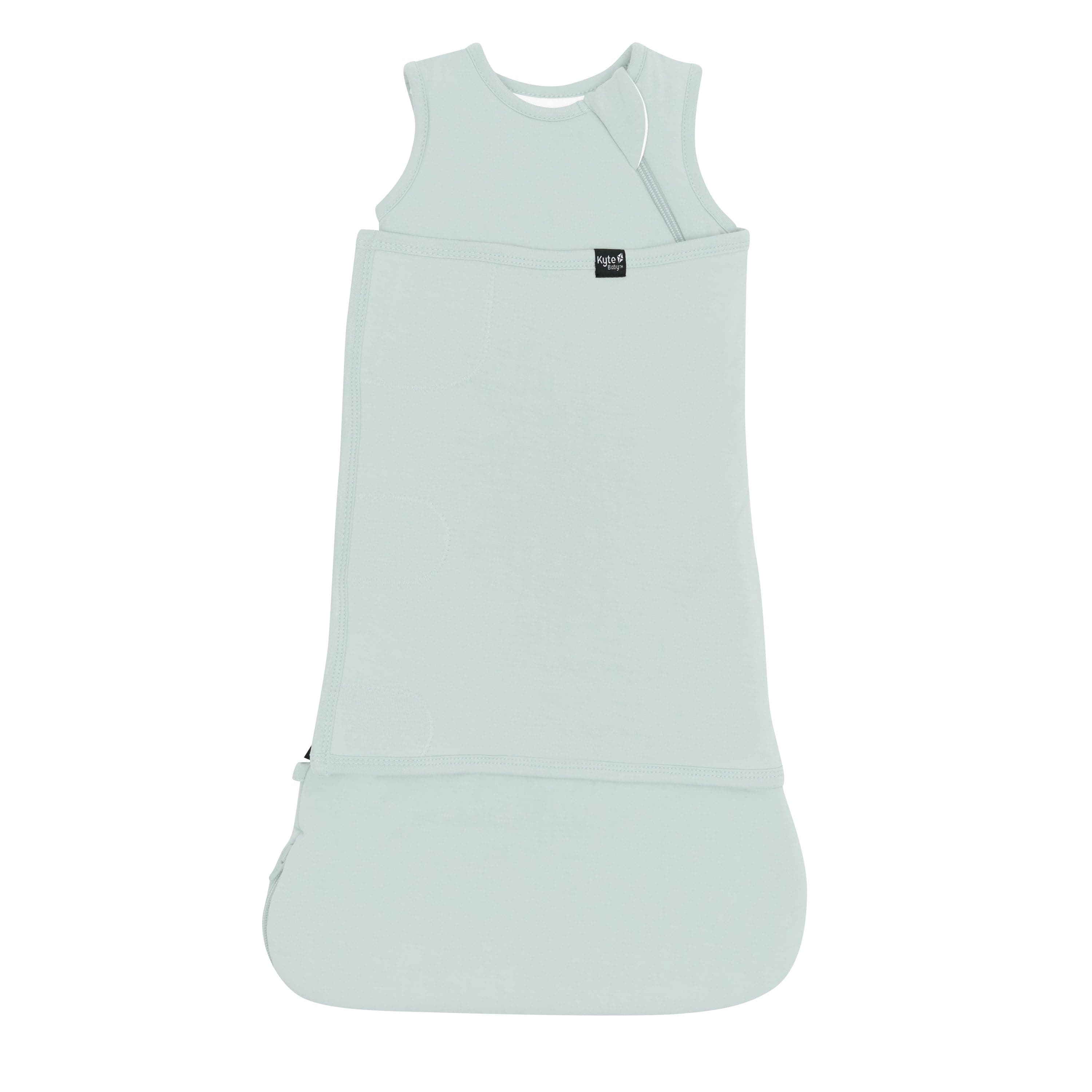 Sleep Bag Swaddler in Sage 1.0 shown swaddled with the Black Kyte Baby logo visible