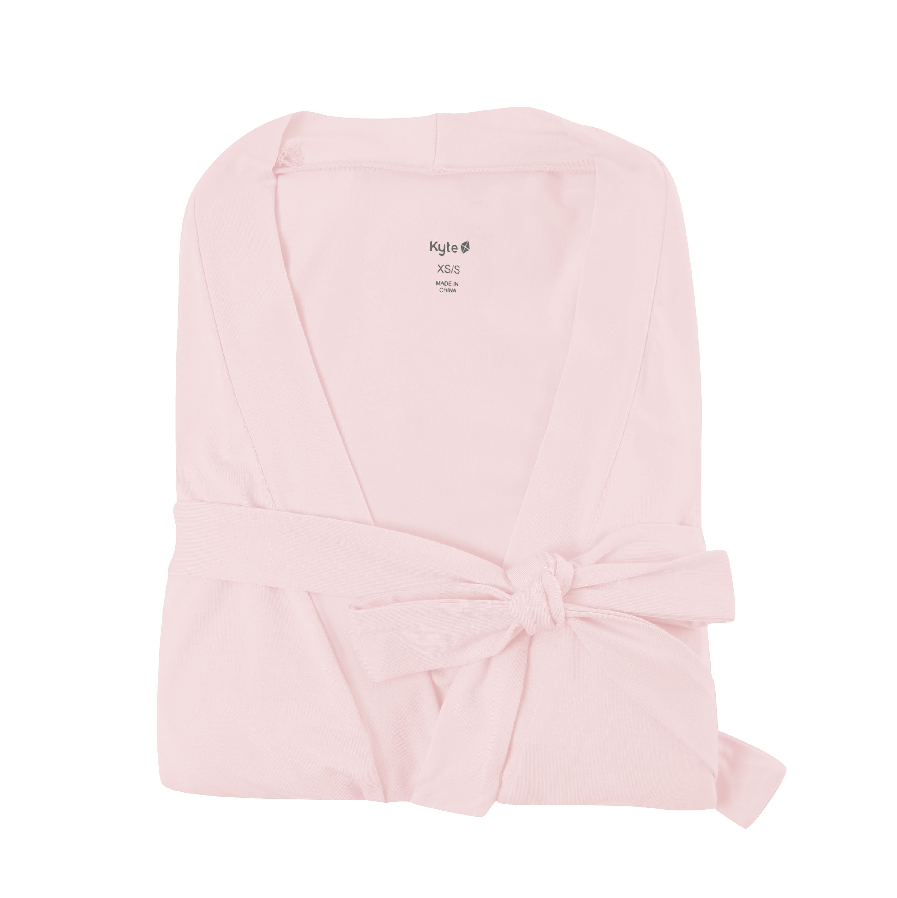 Folded blush pink robe on white backdrop