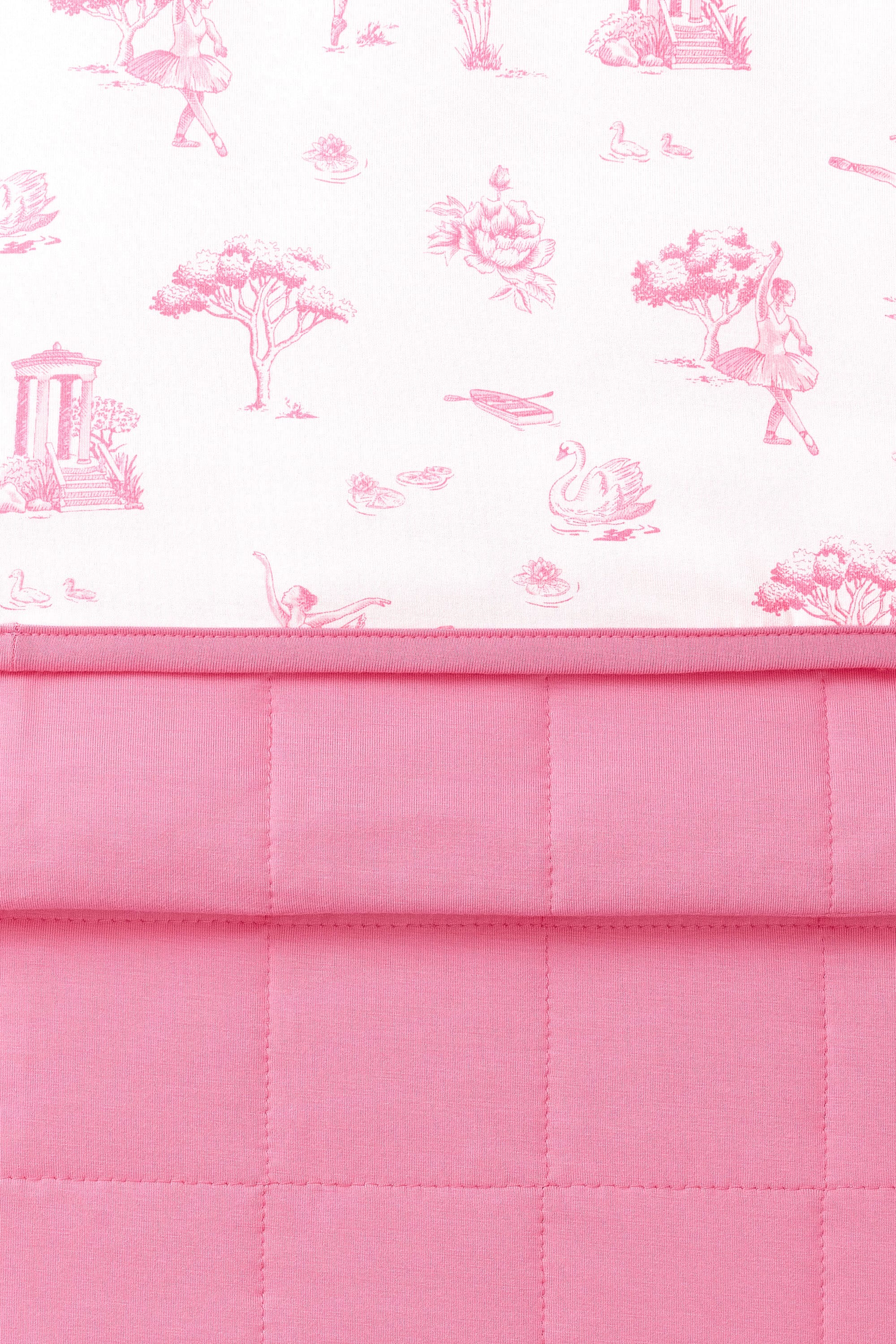 Close up of the Youth Blanket in Toile Ballet 1.0 showing the pink quilted backing and smooth printed top layer