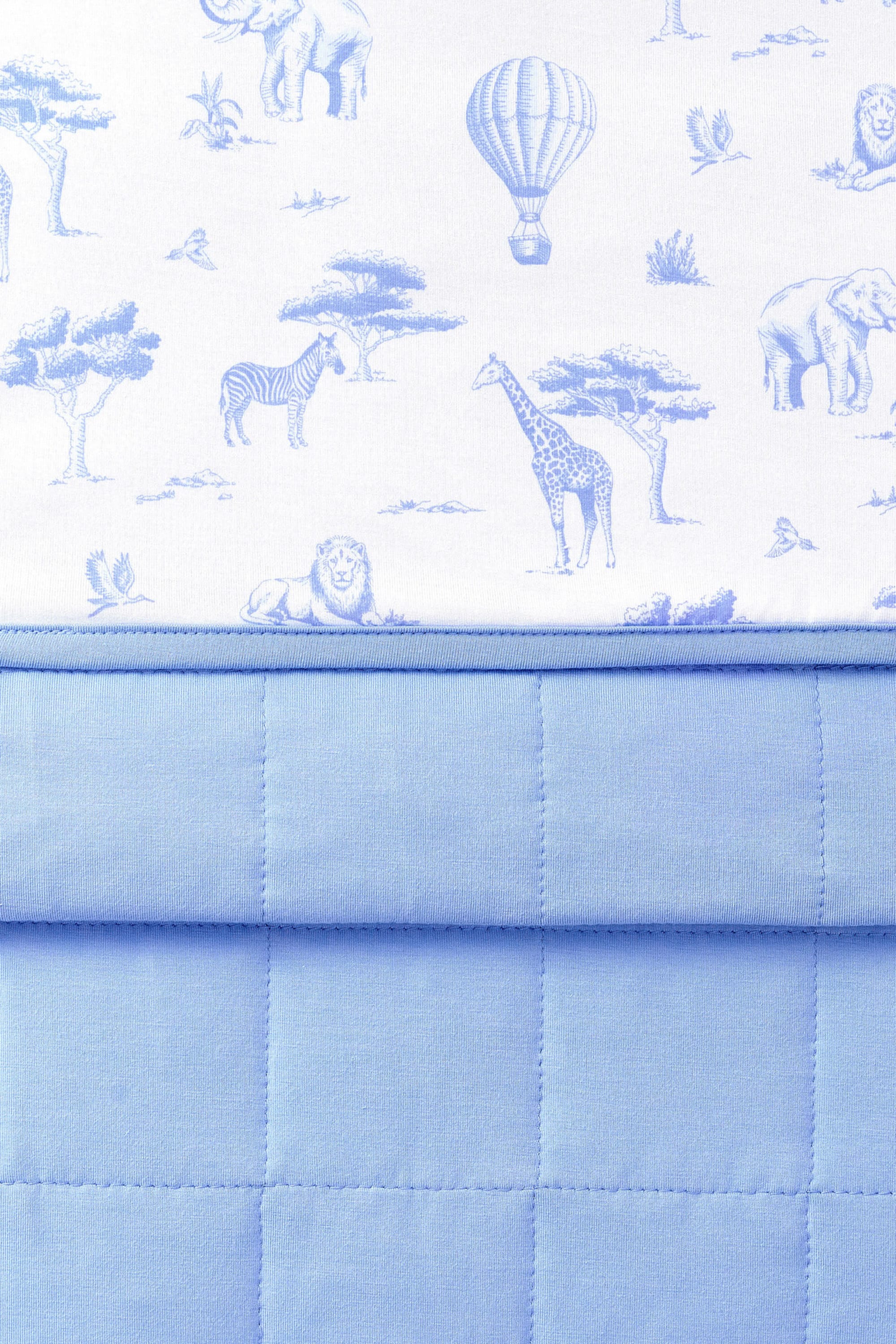 Close up of the Youth Blanket in Toile Safari 1.0 showing the quilted blue backing and smooth printed top layer