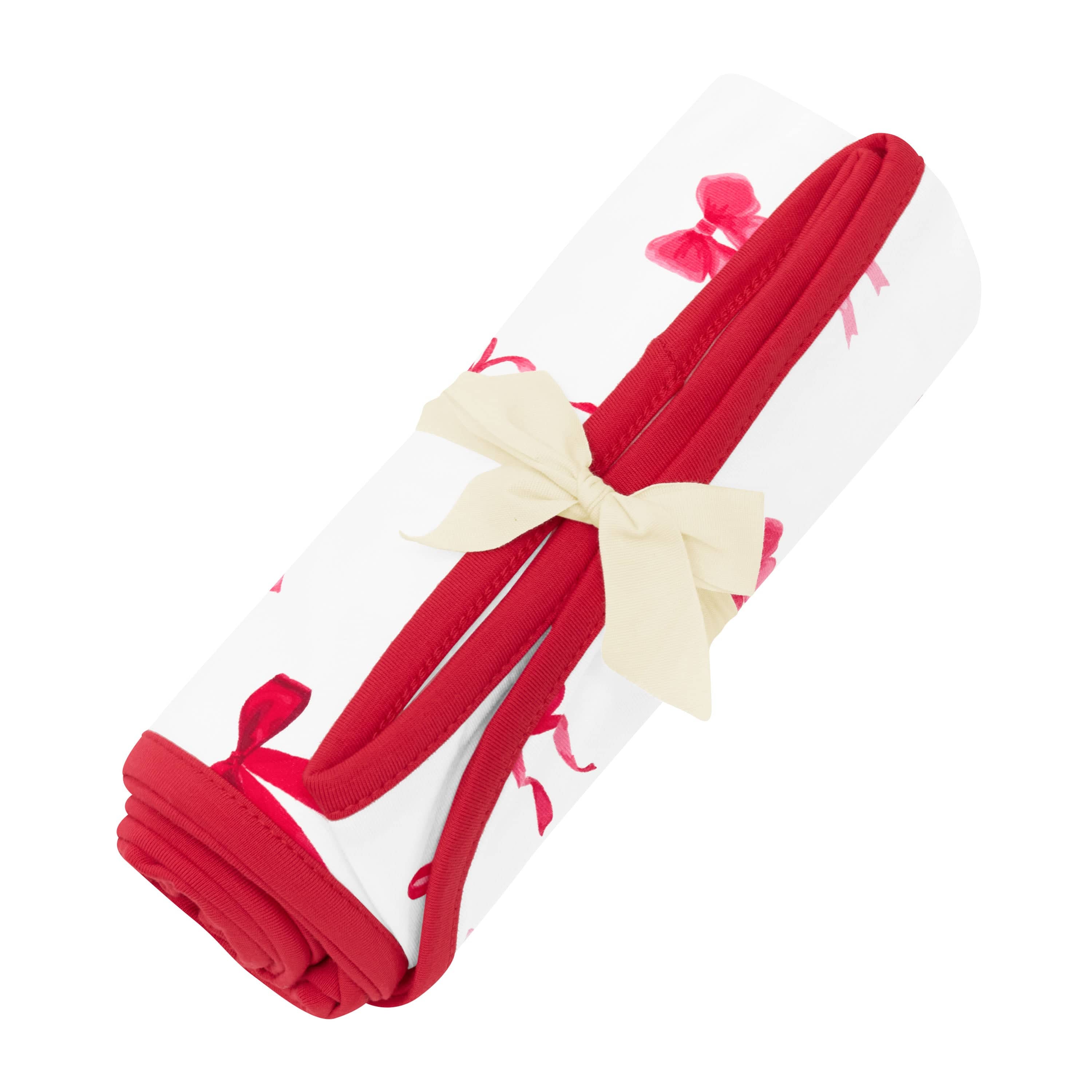 Swaddle Blanket in Small Love Bow shown rolled in its packaging tied with a linen bow