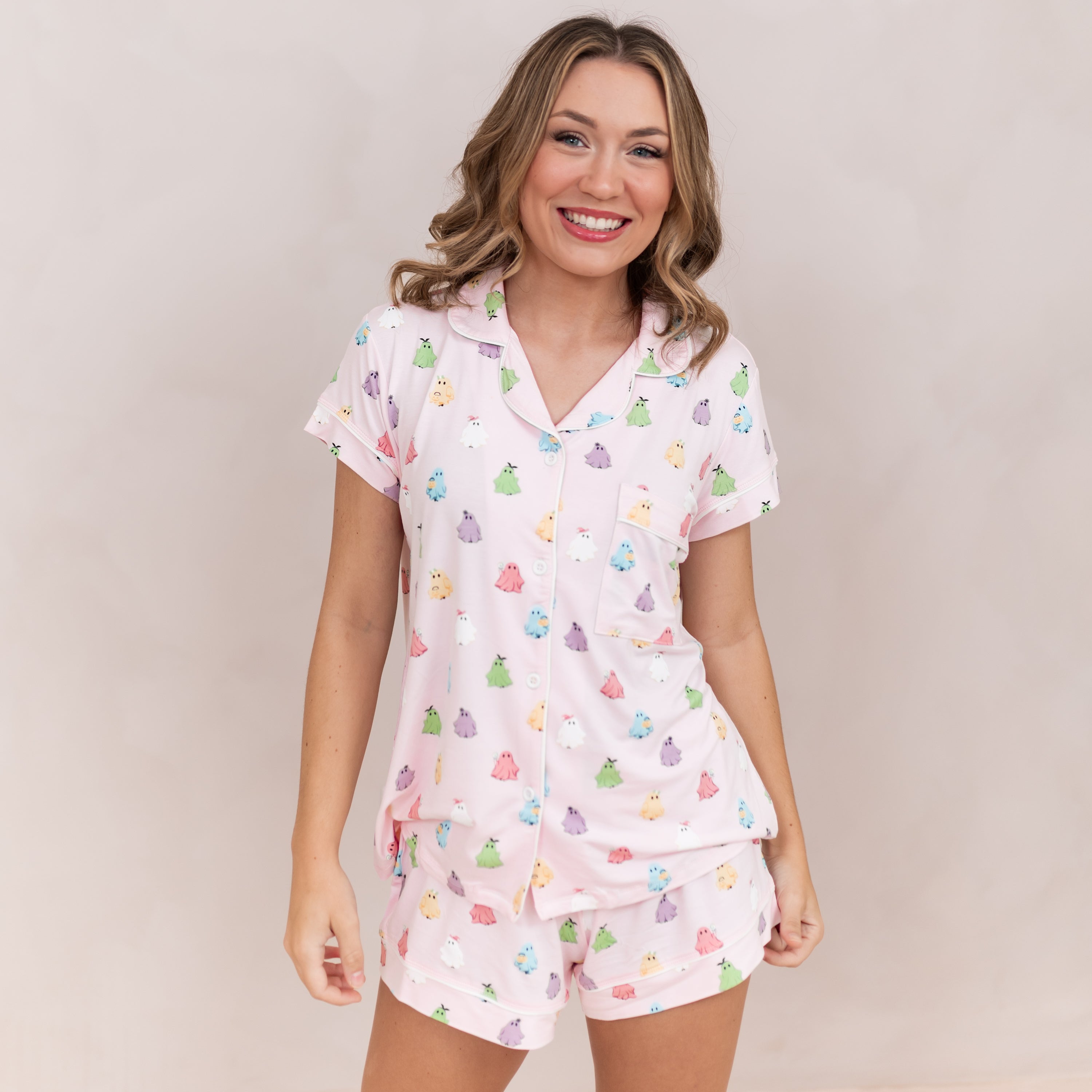 Smiling female model wearing the Women's Short Sleeve Pajama Set in Pastel Ghost in front of a light beige backdrop