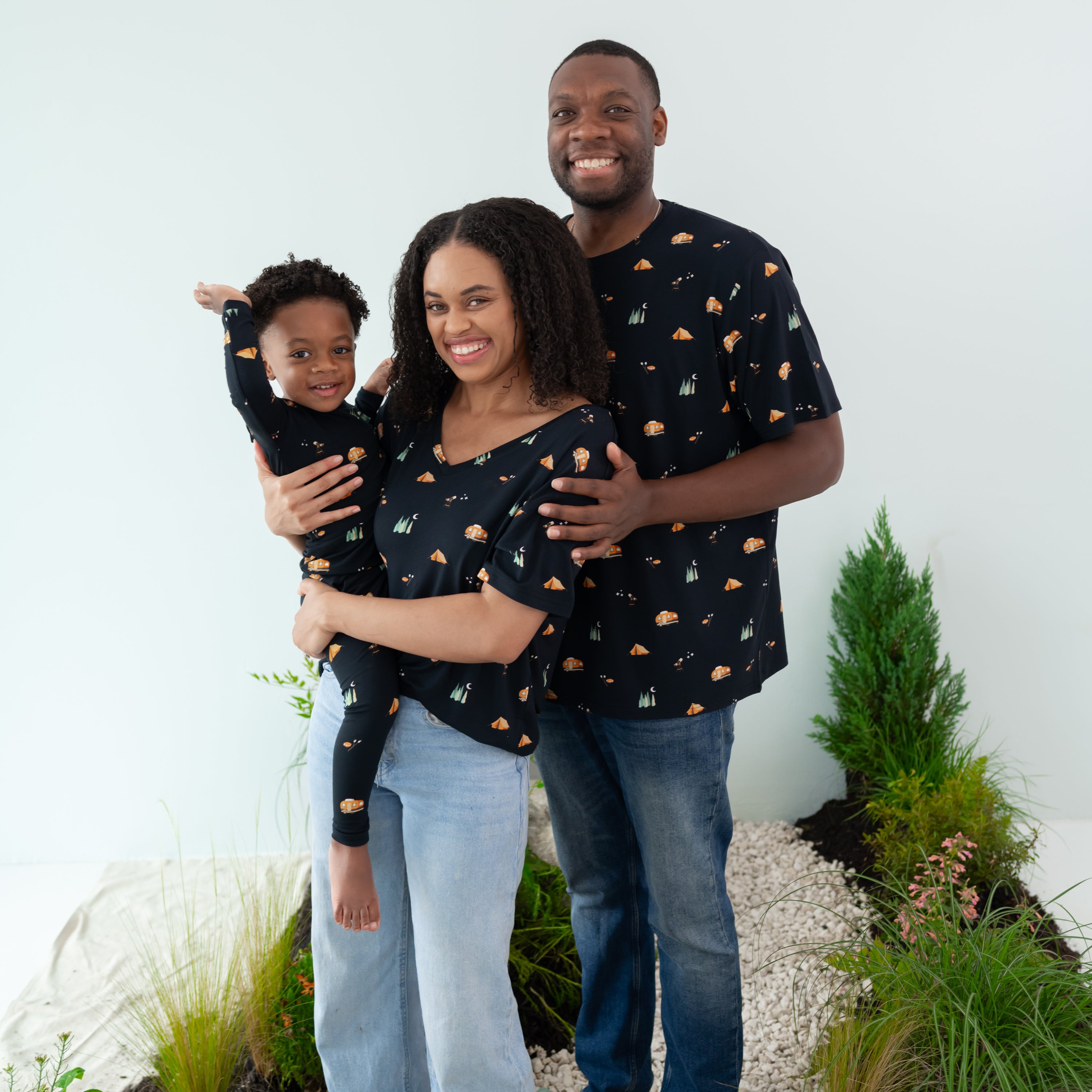 Family wearing the Under the Stars Collection. Father is wearing the Men's Crew Neck, mother is wearing the Women's Relaxed fit V-Neck holding their son who is in long sleeve toddler pajamas
