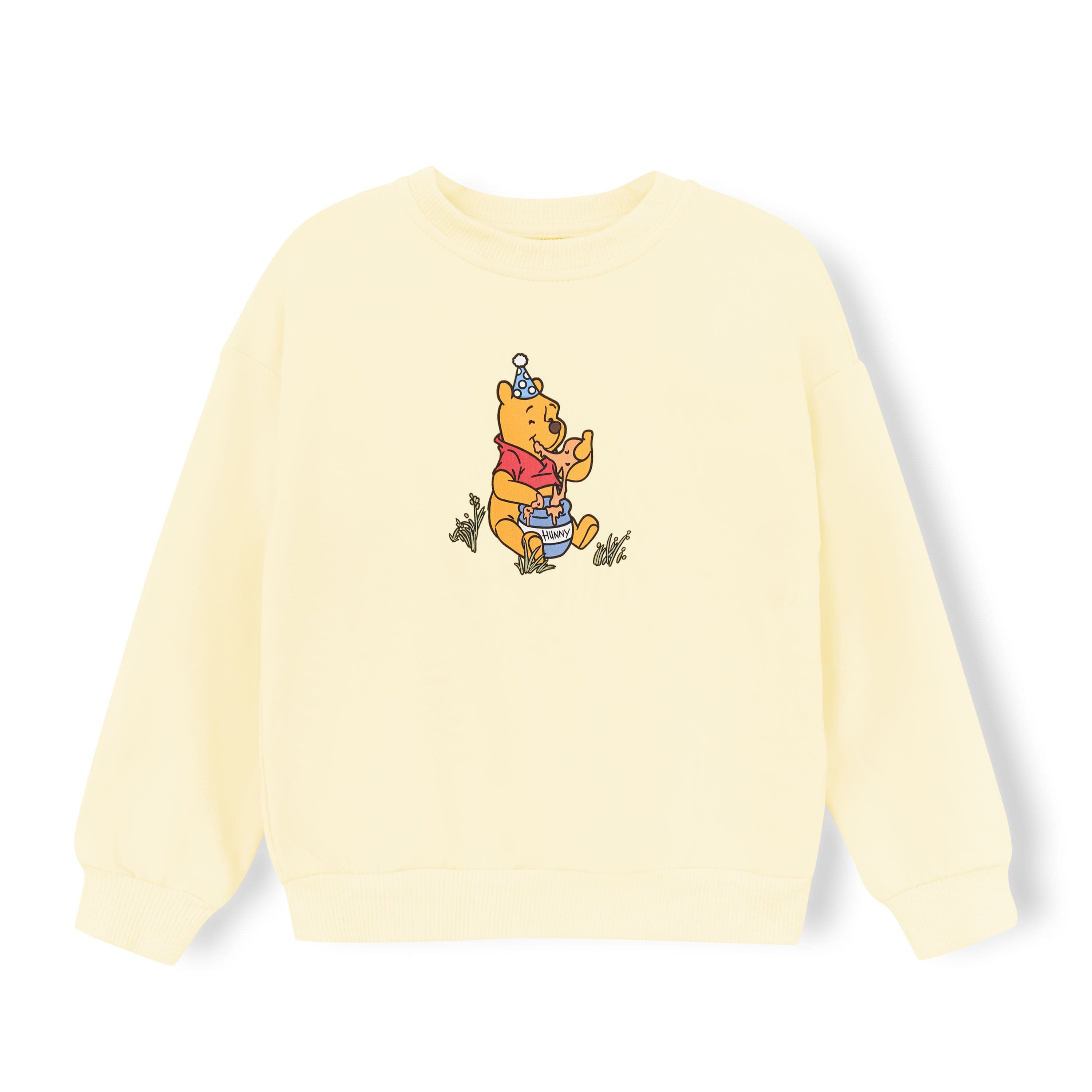 Light yellow sweatshirt with winnie the pooh in the center sitting on the ground eating honey for a honey pot