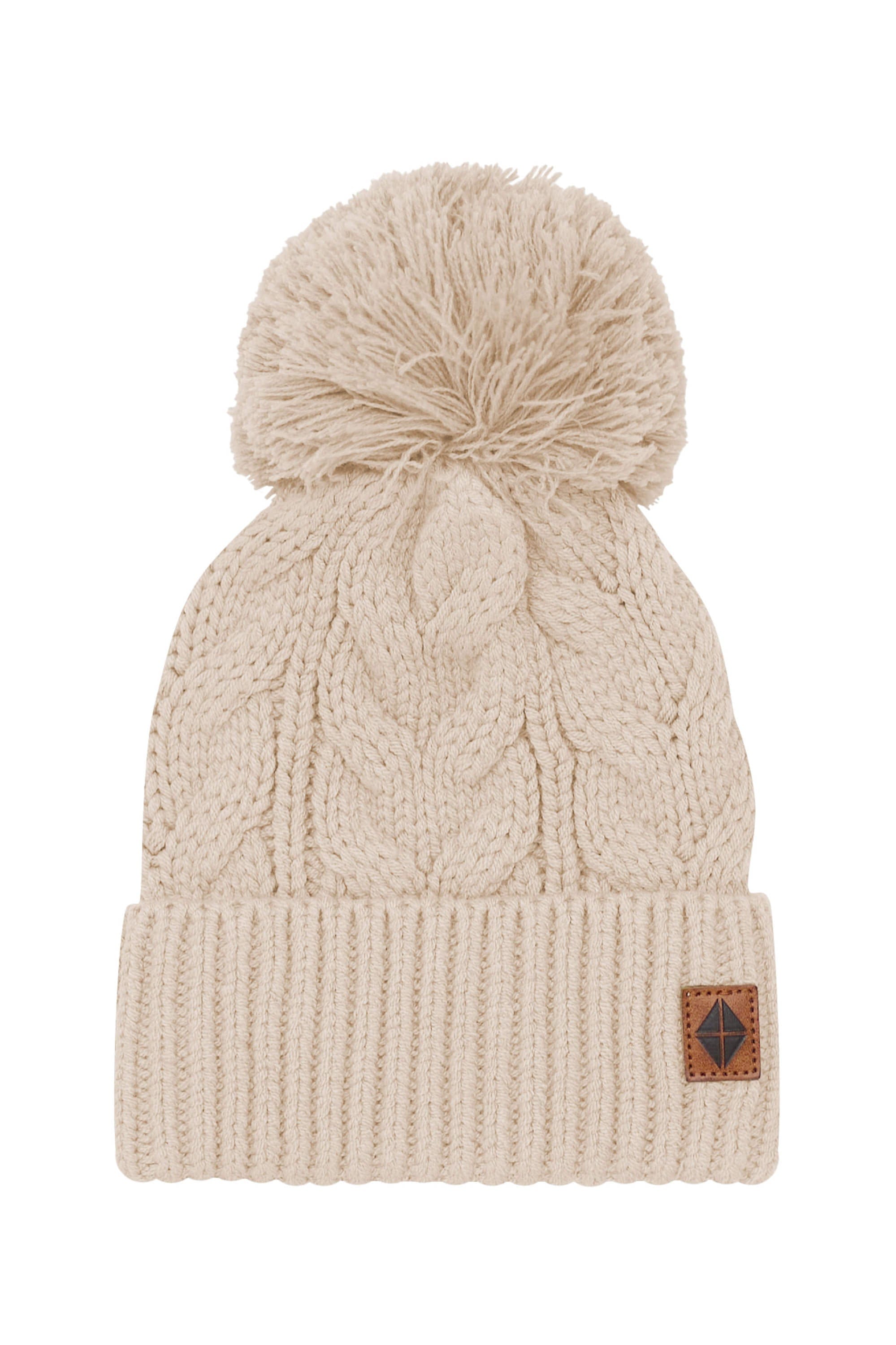 Product photo of the Chunky Cable Knit Beanie in Almond with the Kyte Baby Vegan leather tag visible