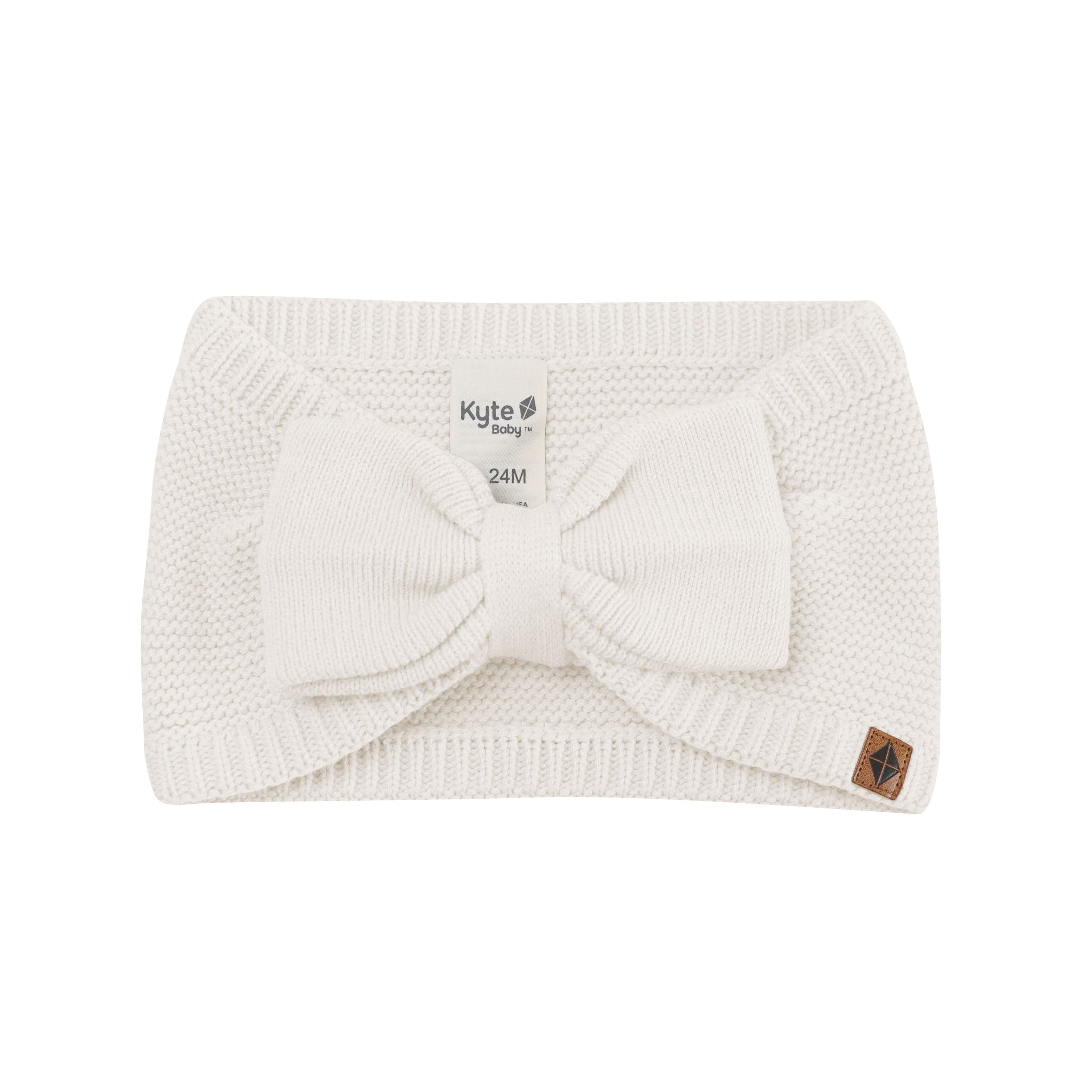 Product photo of the Chunky Knit Bow Headband in Oat with the Kyte Baby vegan leather tag visible