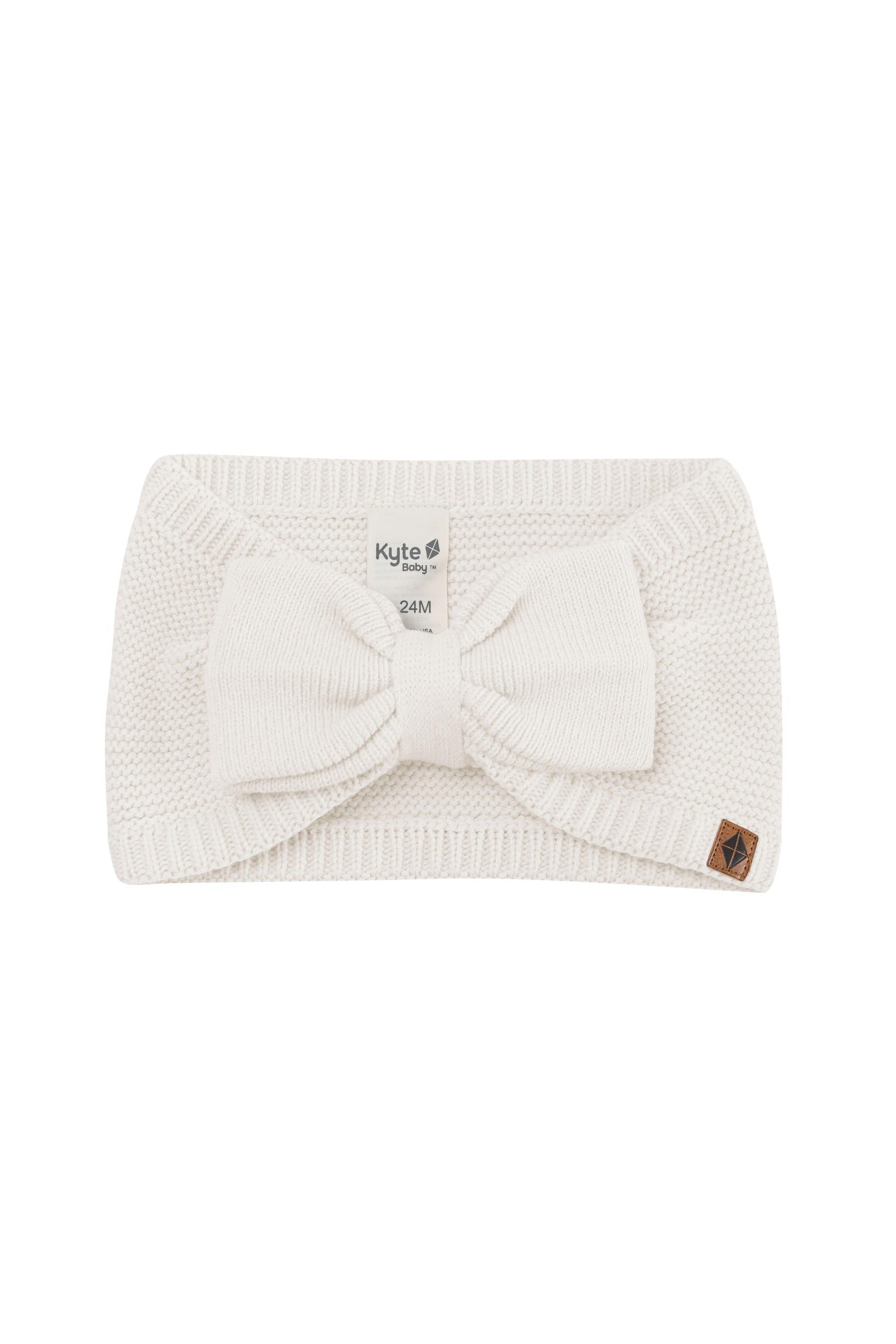 Product photo of the Chunky Knit Bow Headband in Oat with the Kyte Baby vegan leather tag visible