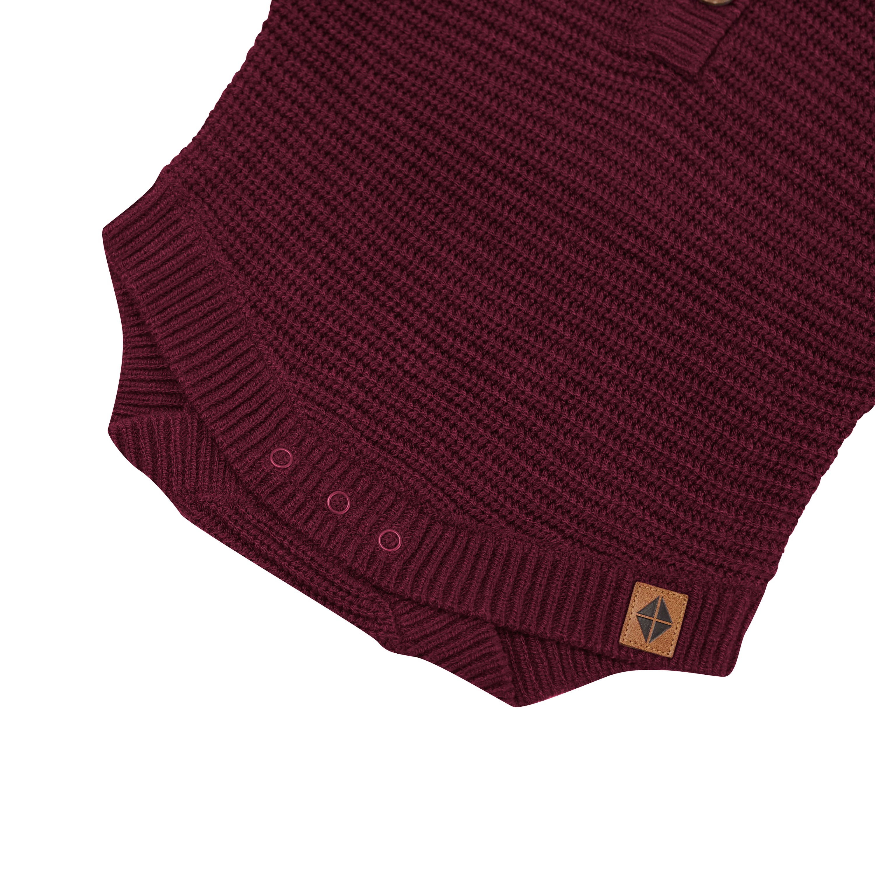 Snap closures shown on the Chunky Knit Romper in Burgundy with the Kyte Baby vegan leather tag visible