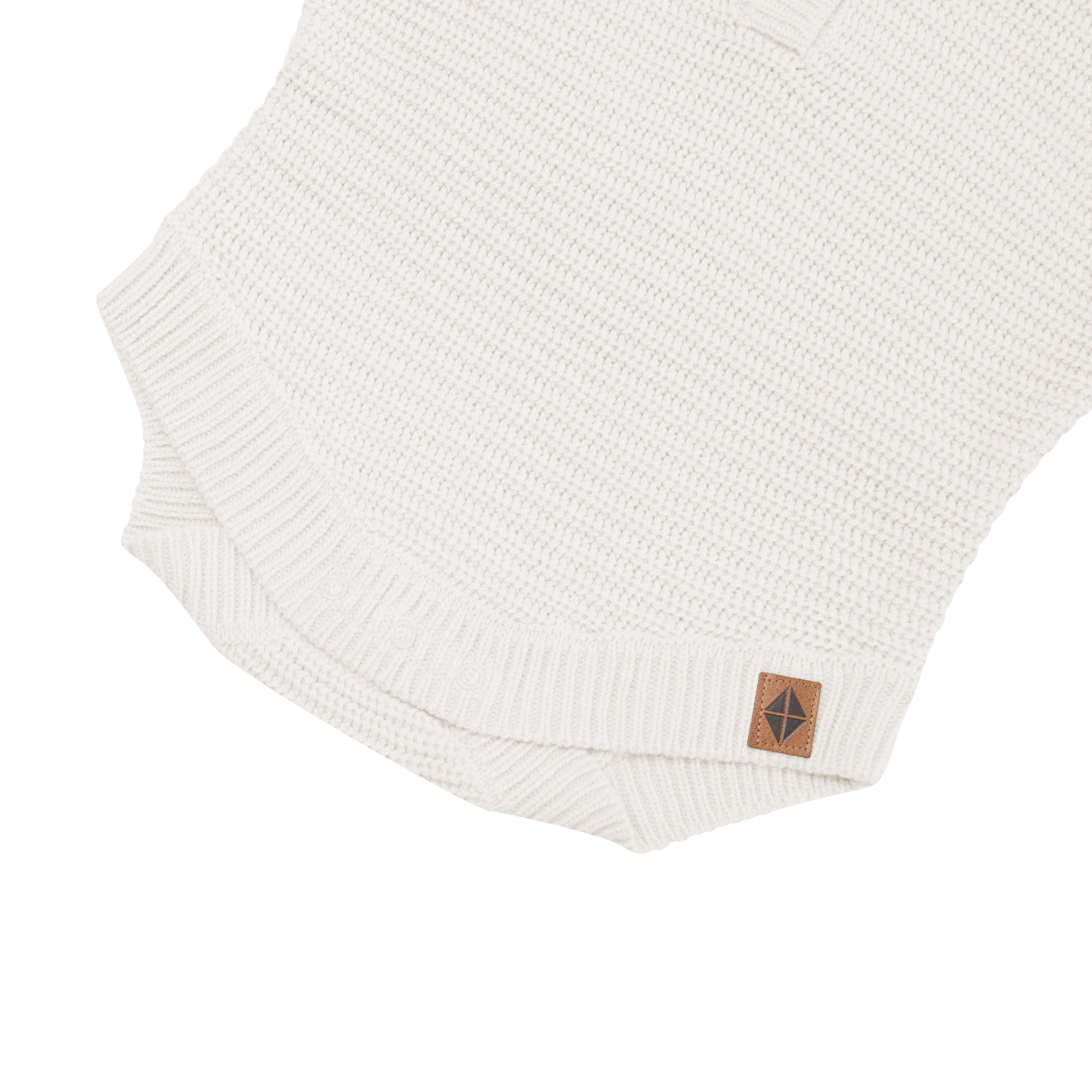 Snap closure shown on the Chunky Knit Romper in Oat with the Kyte Baby vegan leather tag visible