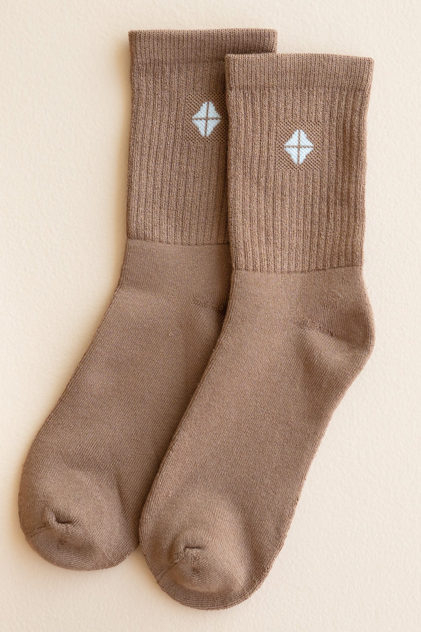 Adult Crew Socks in Latte shown out of package laying side by side on a light beige surface