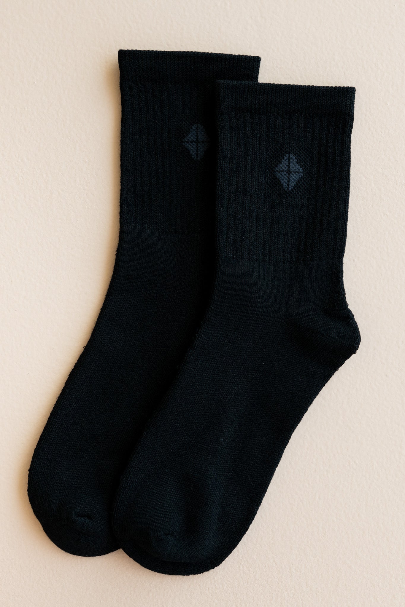 Adult Crew Socks in Midnight shown out of packaging laid side by side on top of a light beige surface
