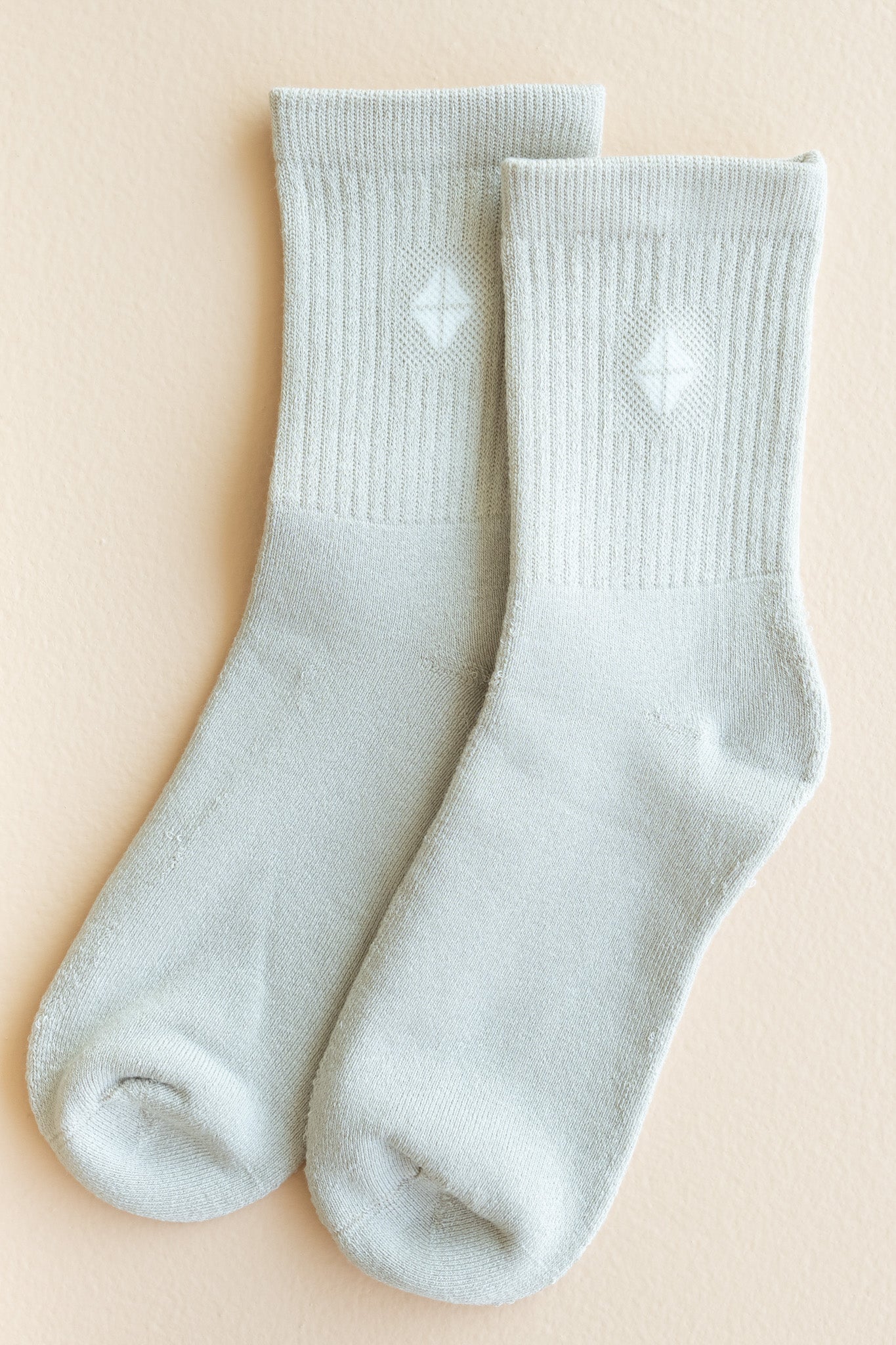 Adult Crew Socks in Oat shown out of package laid side by side on top of a light beige surface