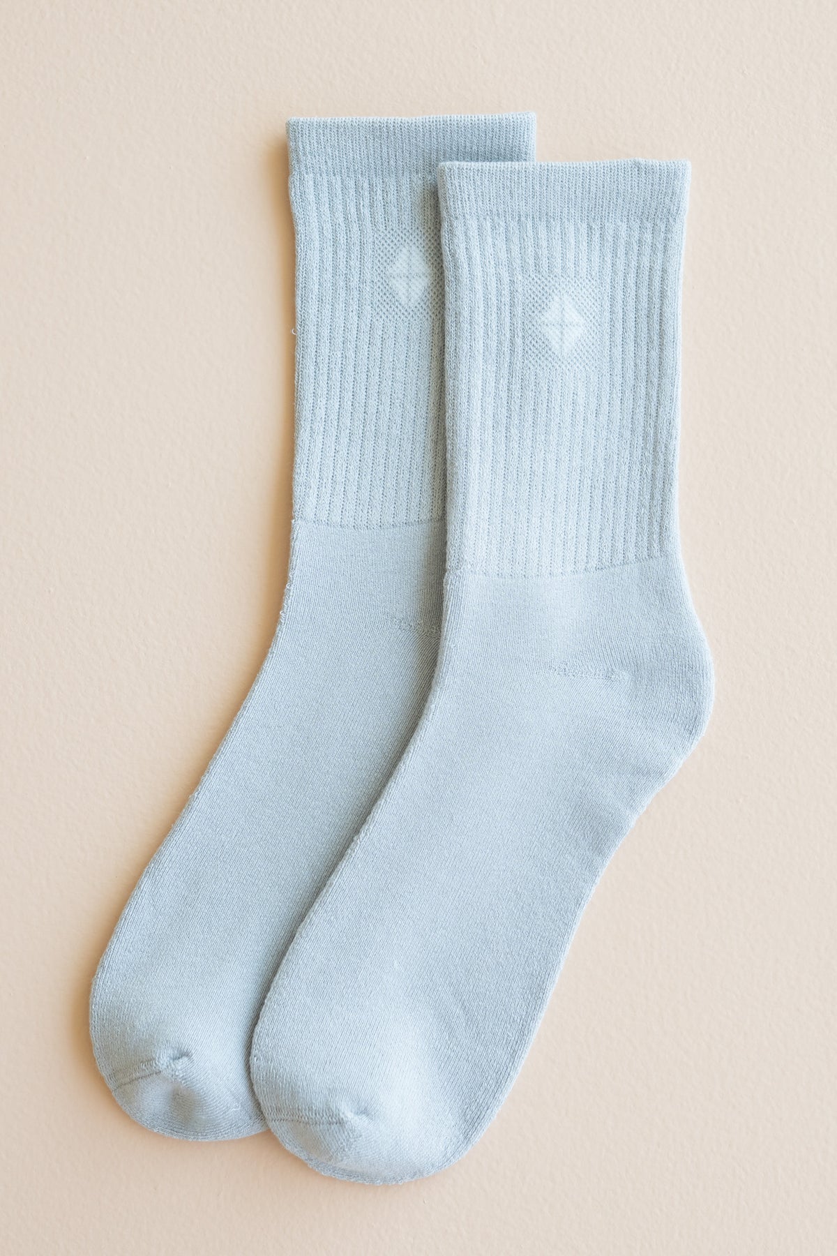 Pair of Adult Crew Socks in Storm out of package laid side by side on a light beige surface