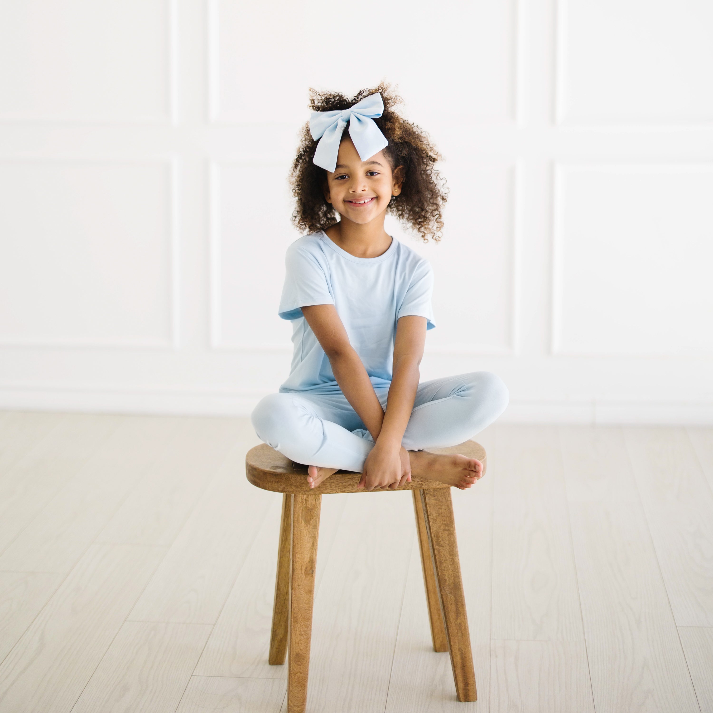 Young girl sitting on a stool wearing the Large Alligator Clip Bow in Breeze