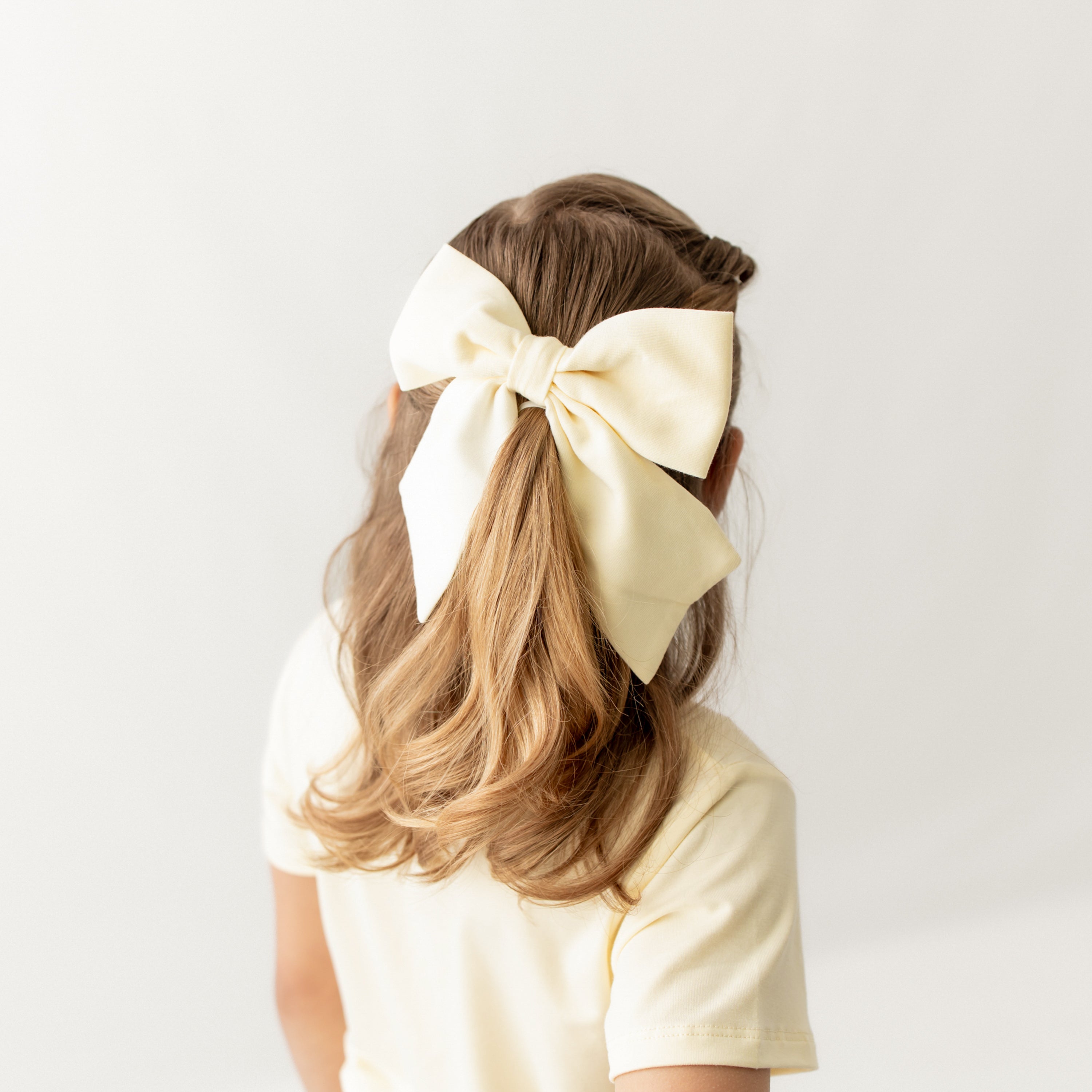 Large Alligator Clip Bow in Chamomile shown in a young girls hair