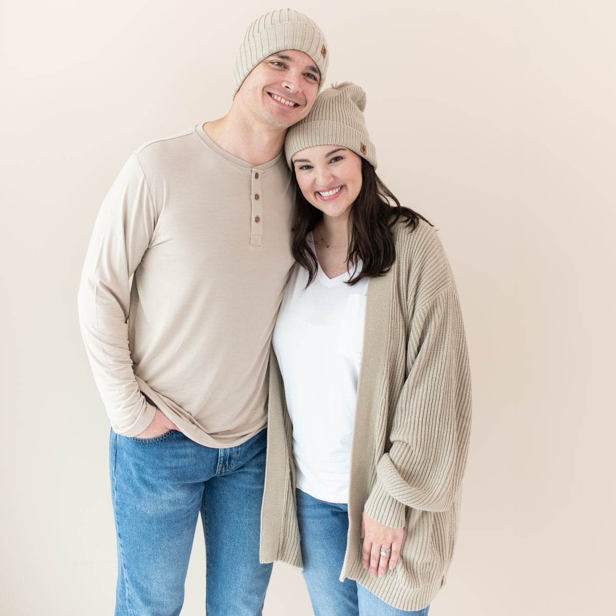Couple modeling almond kyte pieces including men's henley tee, chunky knit cardigan and beanies