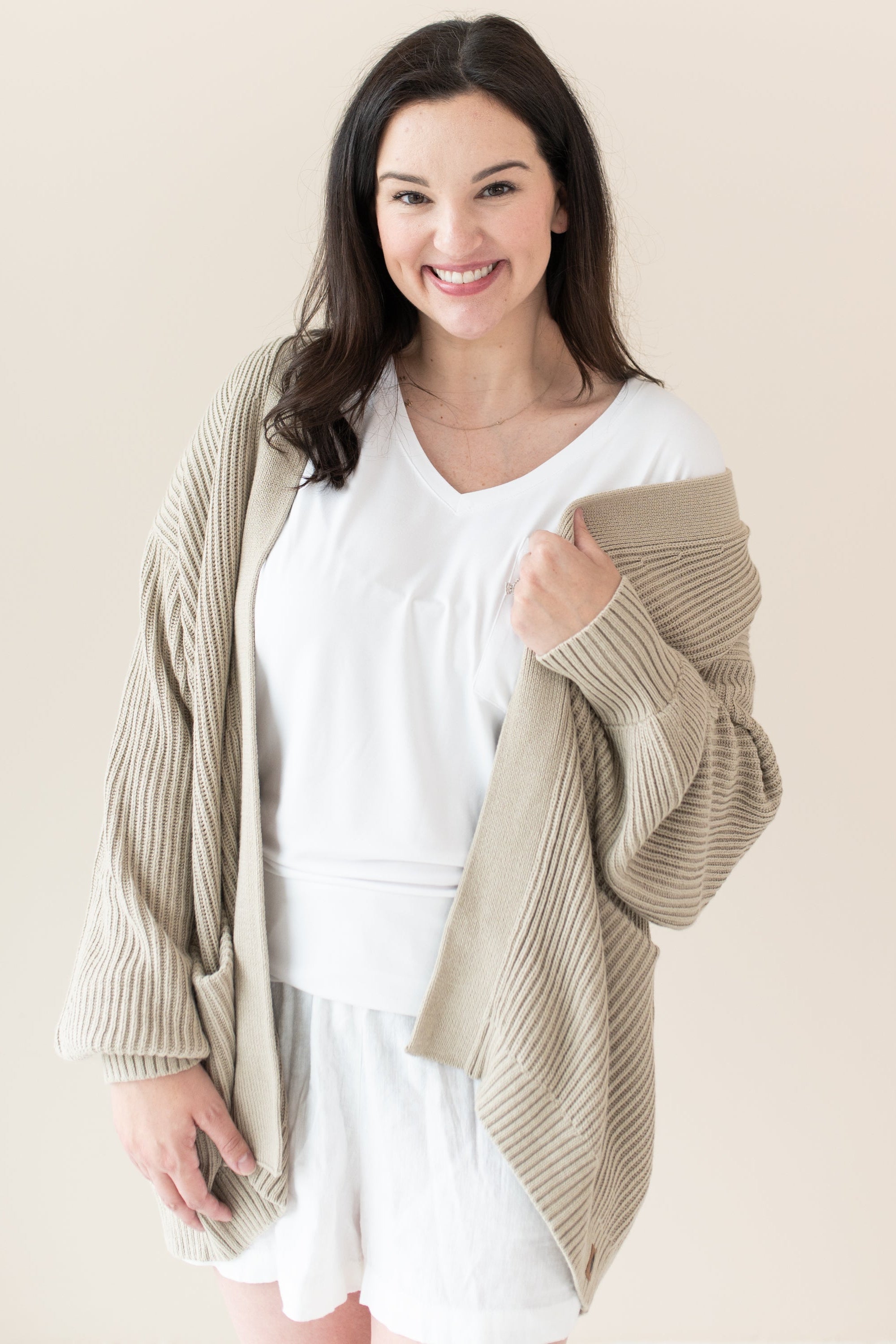 Woman modeling Chunky Knit Women's Oversized Cardigan in Almond with a white tshirt and shorts