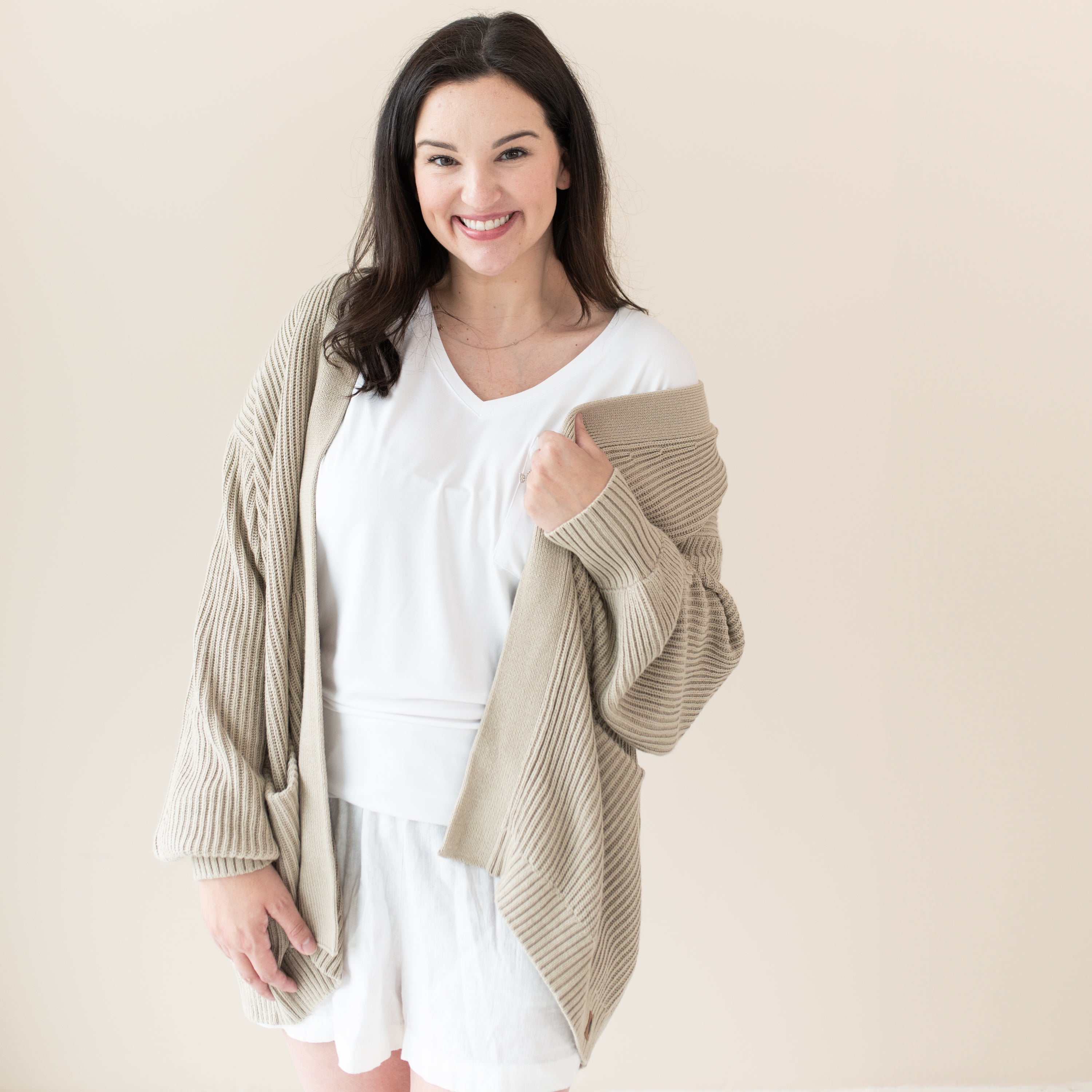 Woman modeling Chunky Knit Women's Oversized Cardigan in Almond with a white tshirt and shorts
