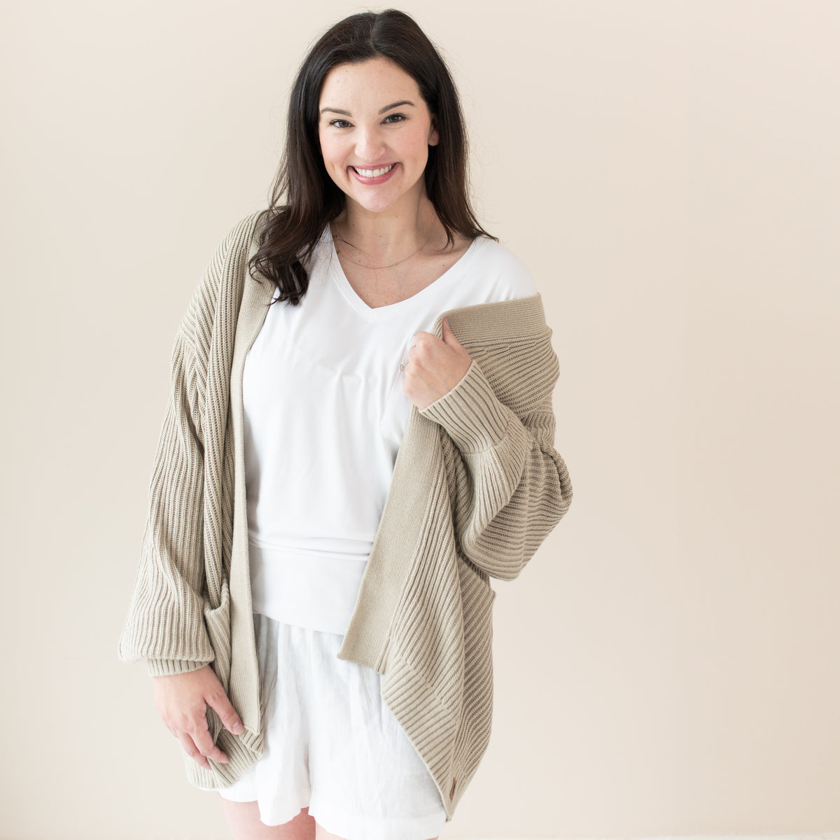 Woman modeling Chunky Knit Women's Oversized Cardigan in Almond with a white tshirt and shorts