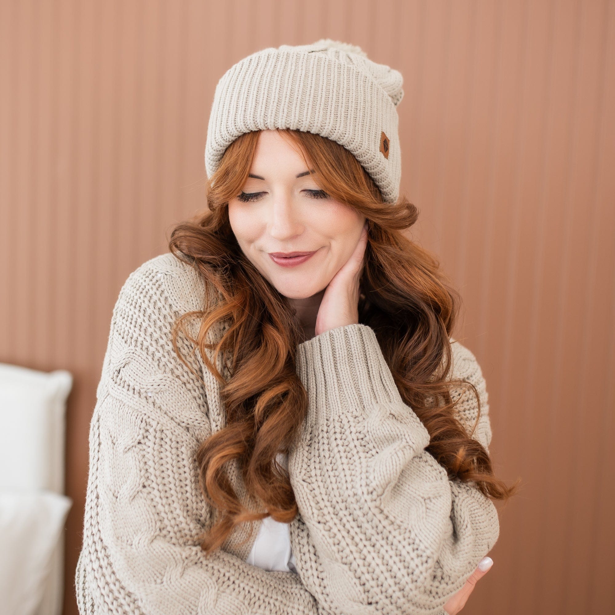 Female model wearing the Cable Knit Adult Pom Beanie in Almond paired with a matching Cable Knit Cardigan