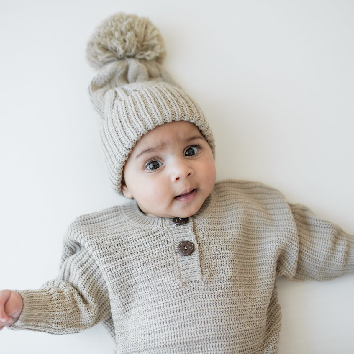 Close up of the Chunky Cable Knit Beanie in Almond shown on an infant wearing the Chunky knit romper in Almond