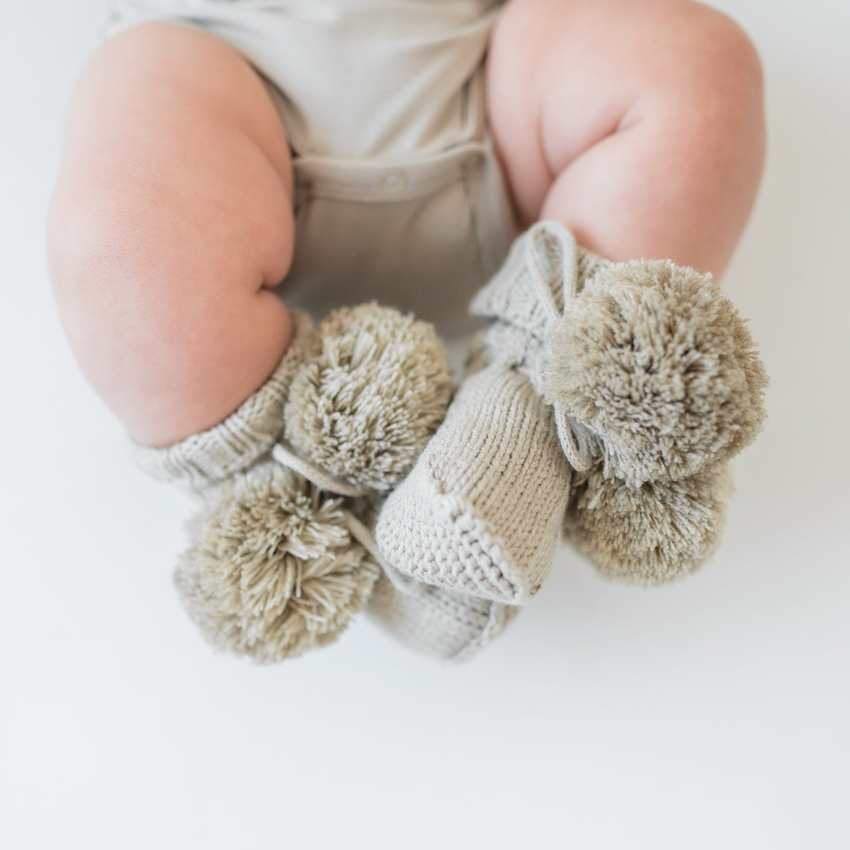 Close up of the Knit Booties in Almond shown on an infant