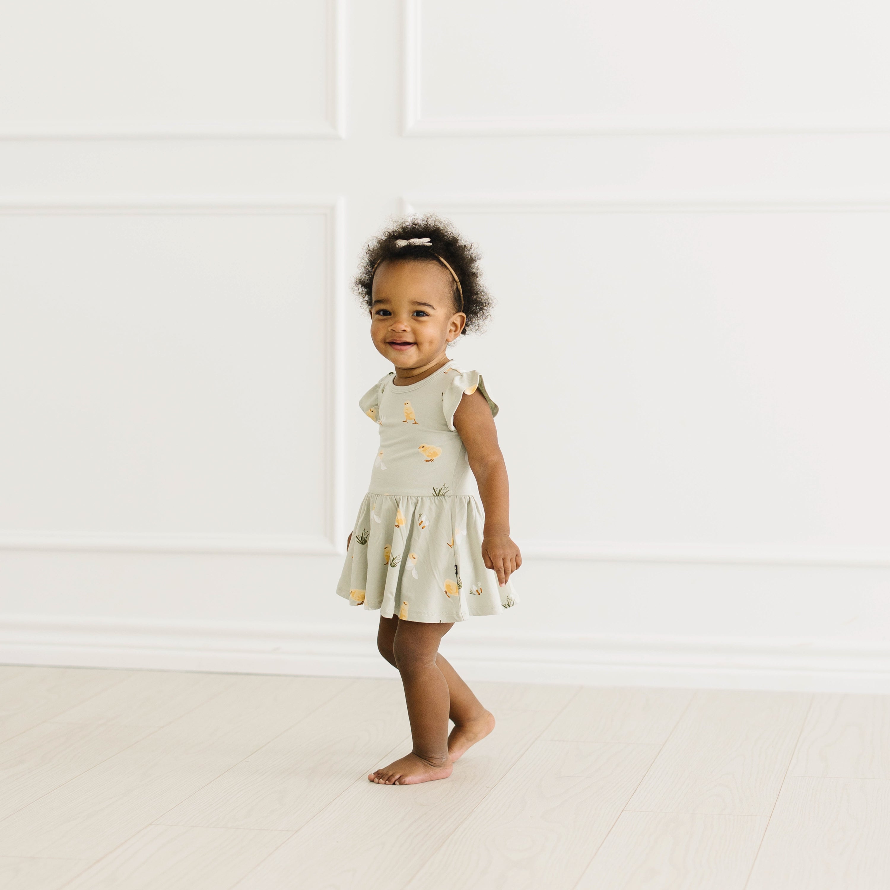 Toddler wearing Twirl Bodysuit Dress with flutter sleeves in Aloe Chick